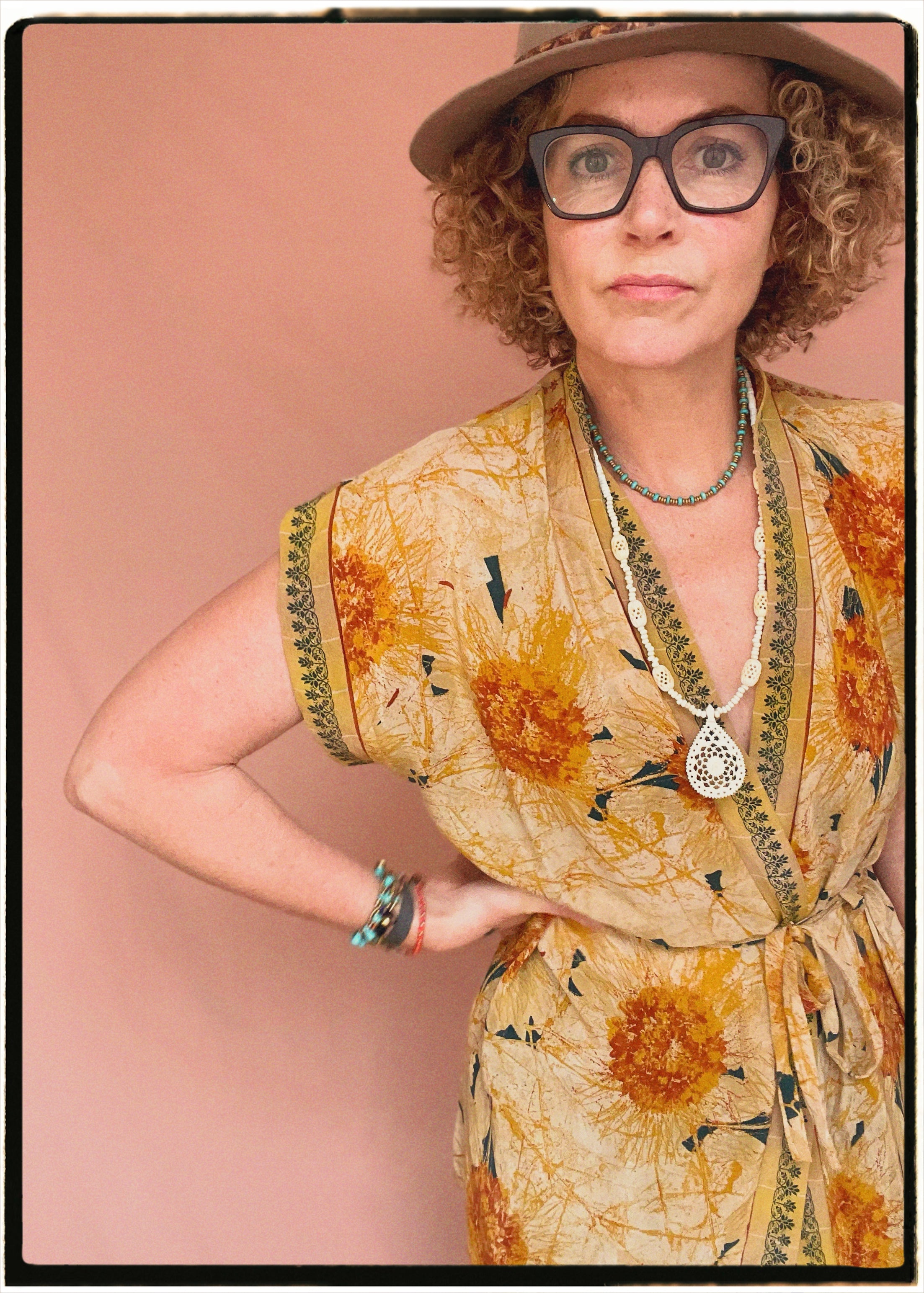 Woman wearing a bohemian style balloon sleeved patterned blouse made from vintage repurposed Indian silk crepe sari in front of a plain background