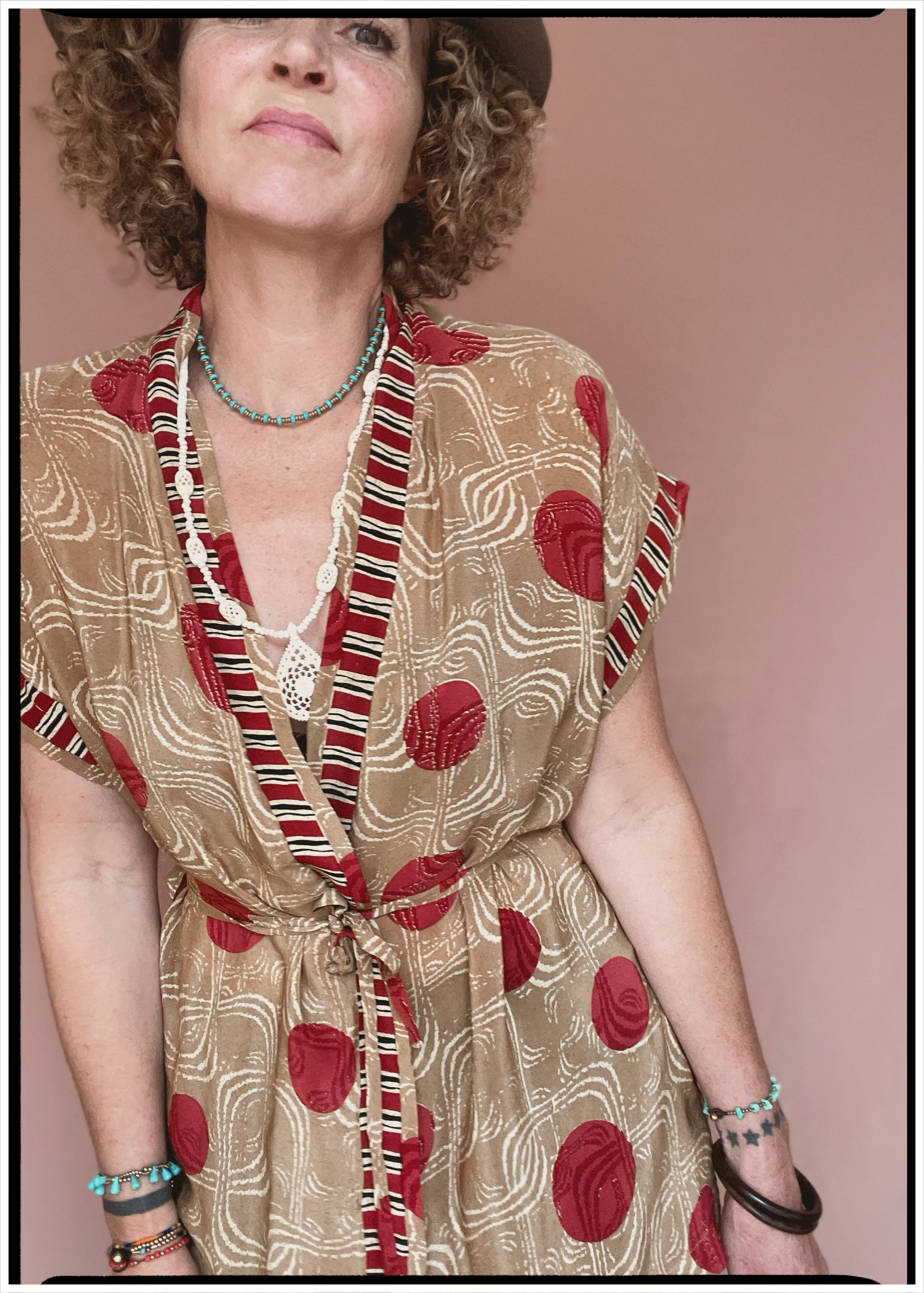 Woman wearing a bohemian style balloon sleeved patterned blouse made from vintage repurposed Indian silk crepe sari in front of a plain background