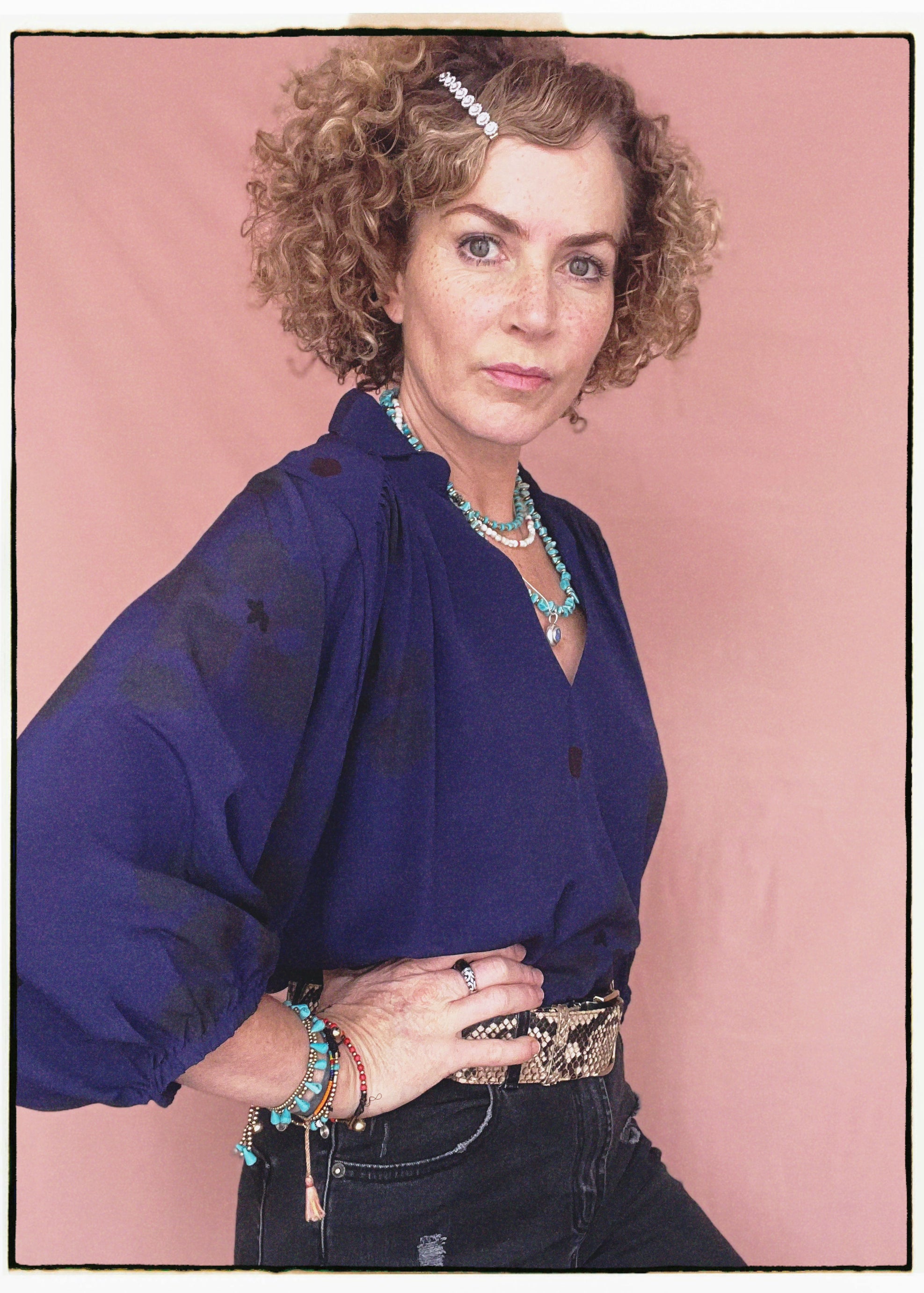 Woman wearing a bohemian style balloon sleeved blouse made from vintage repurposed Indian silk crepe sari in front of a plain background