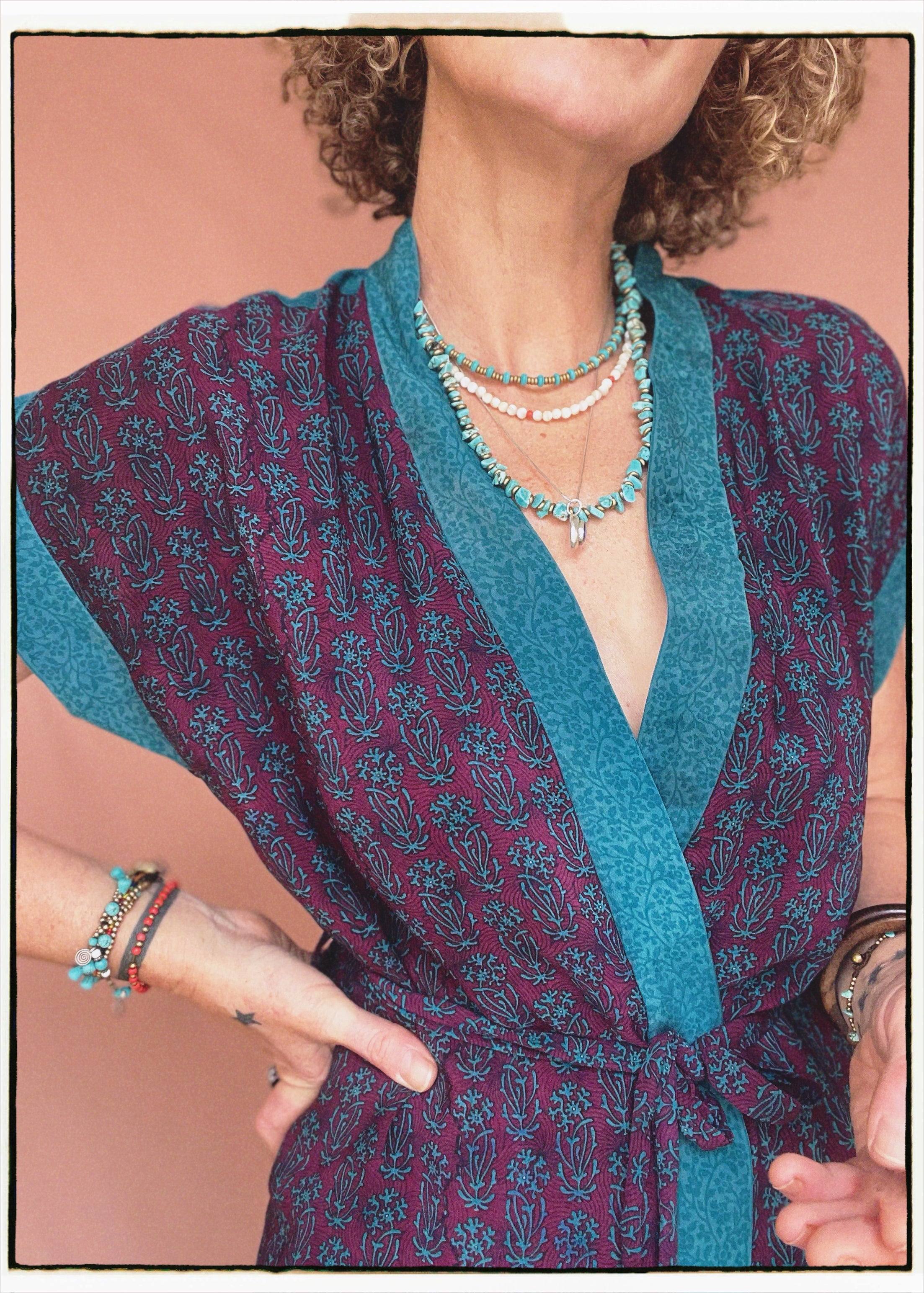 Woman wearing a bohemian style balloon sleeved patterned blouse made from vintage repurposed Indian silk crepe sari in front of a plain background