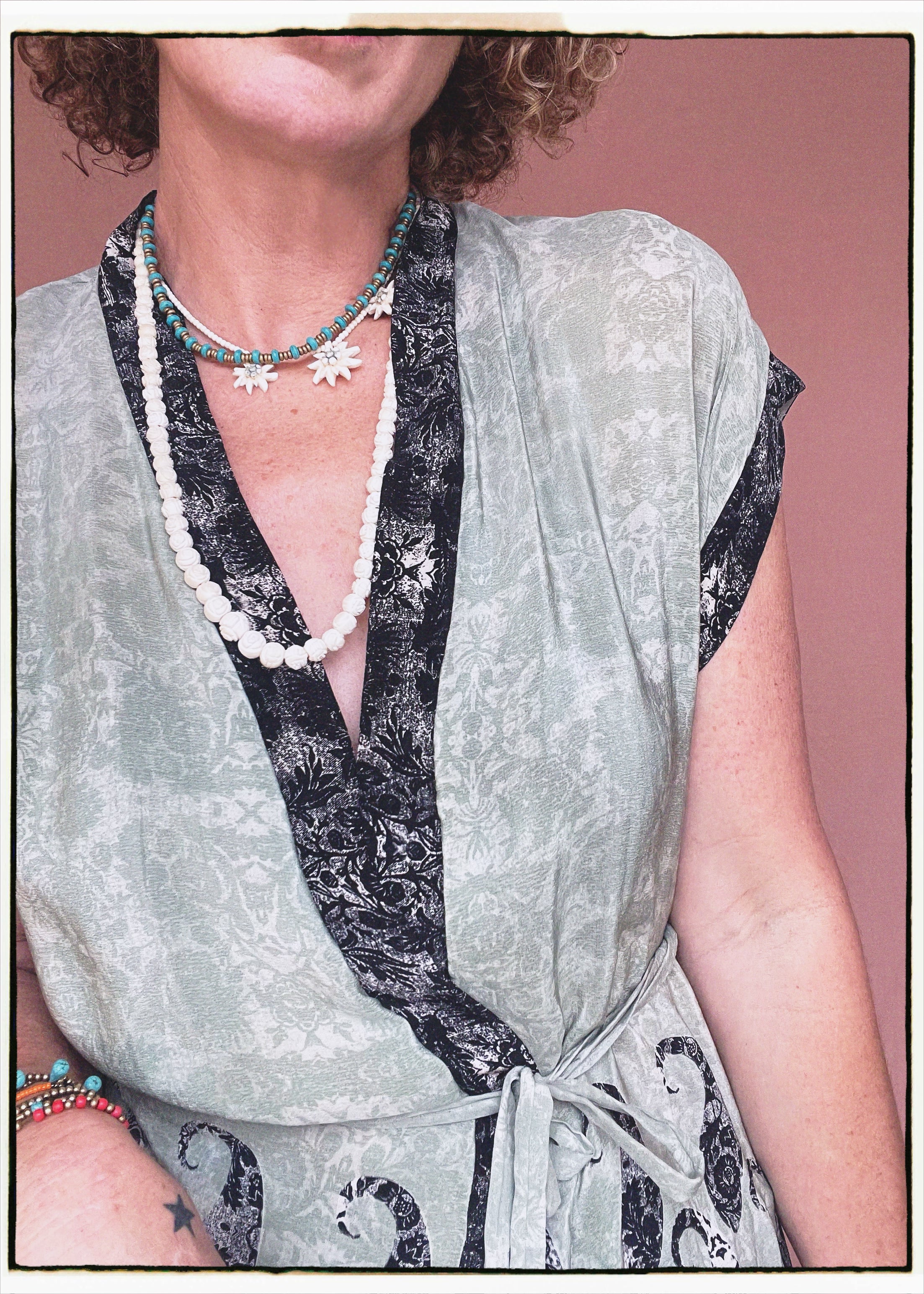 Woman wearing a bohemian style balloon sleeved patterned blouse made from vintage repurposed Indian silk crepe sari in front of a plain background
