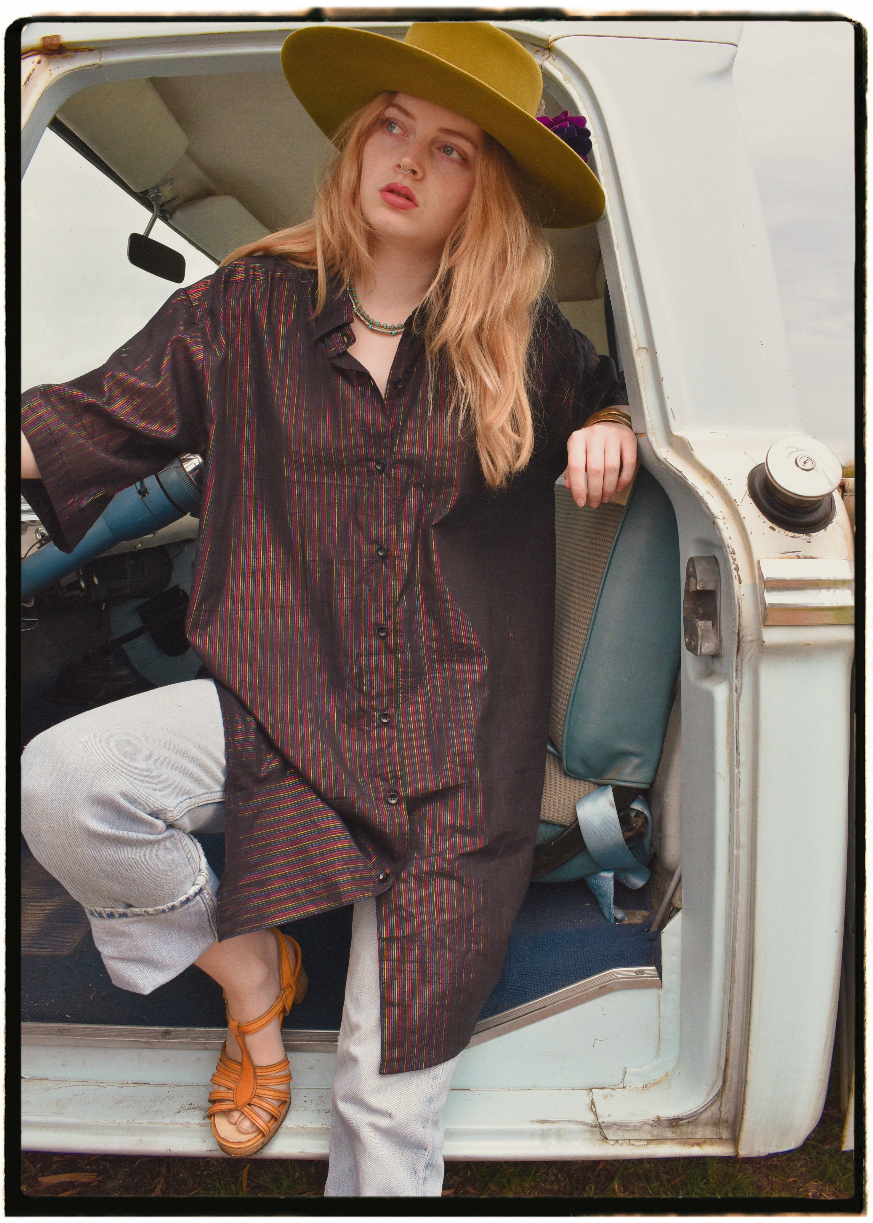 Woman wearing a bohemian style balloon sleeved blouse made from vintage Indian repurposed silk crepe saree sitting in the back of a vintage car with a scenic background
