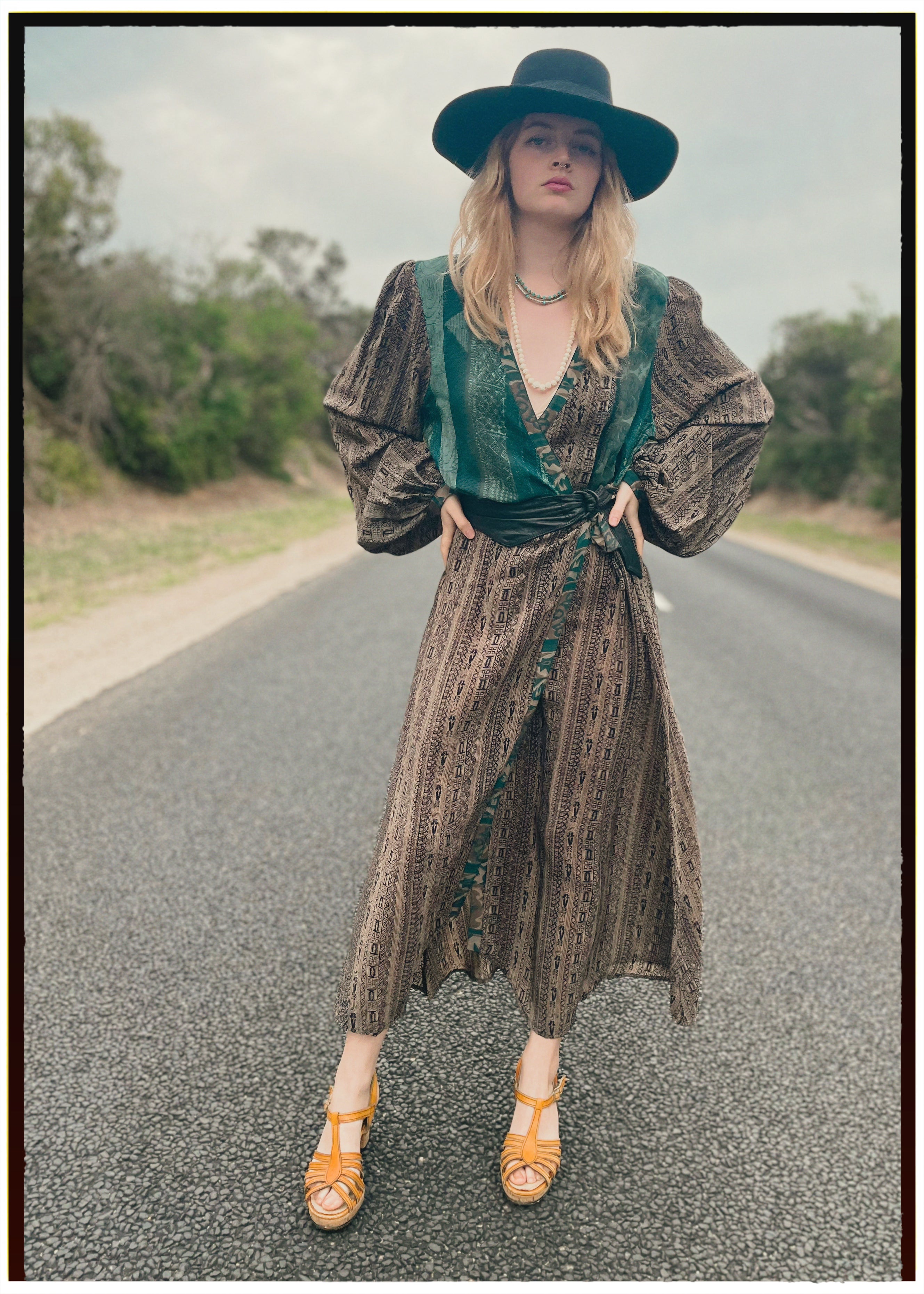 Woman wearing a bohemian style balloon sleeved wrap dress made from vintage repurposed Indian silk crepe sari in front of a plain
