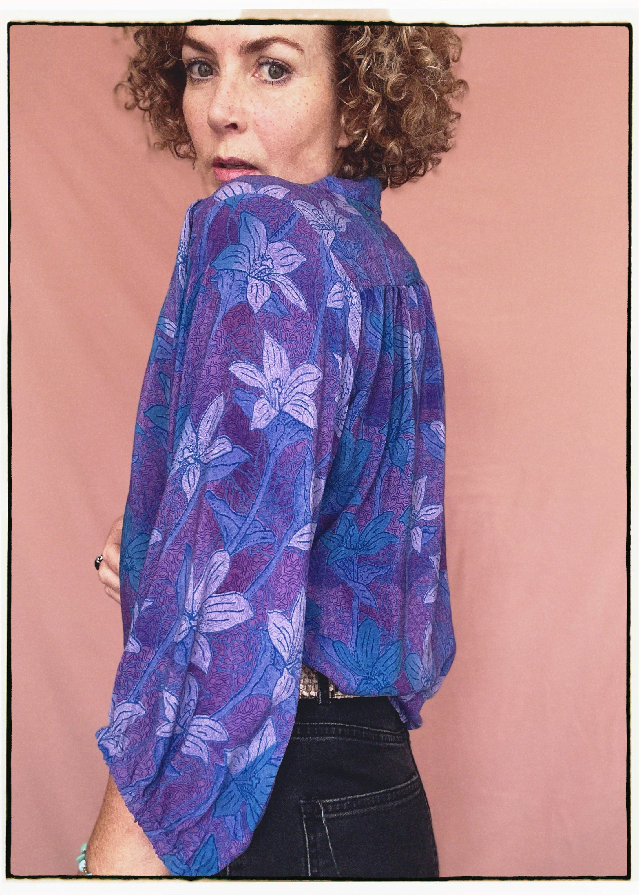 Woman wearing a bohemian style balloon sleeved patterned blouse made from vintage repurposed Indian silk crepe sari in front of a plain background