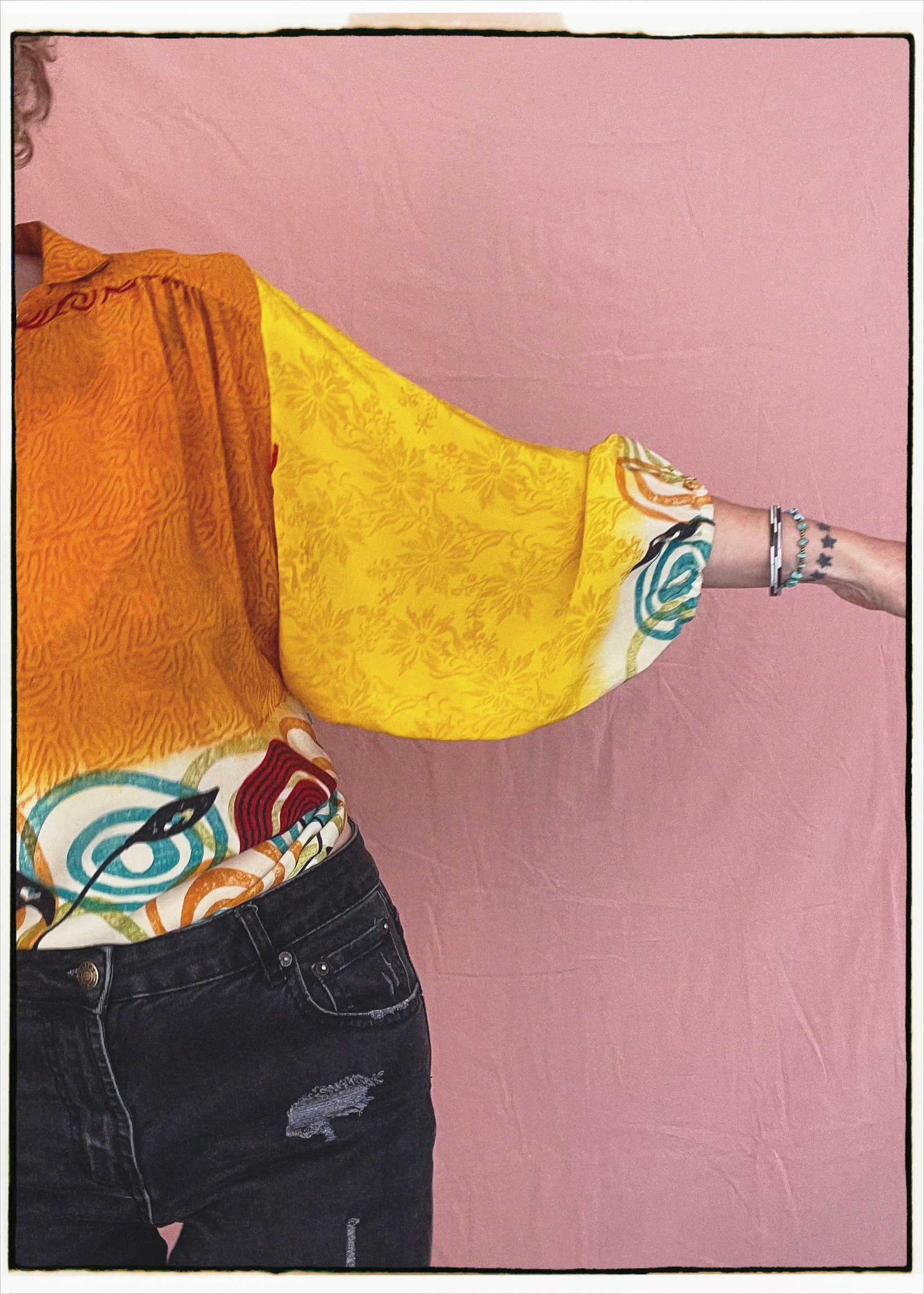 Woman wearing a bohemian style balloon sleeved blouse made from vintage repurposed Indian silk crepe sari in front of a plain background