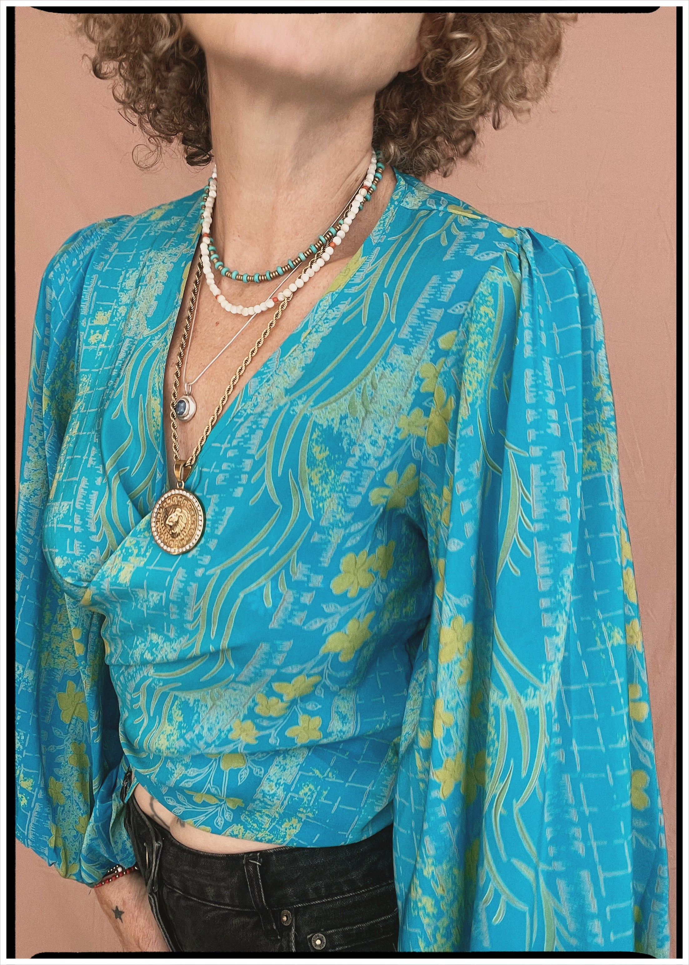 Woman wearing a bohemian style balloon sleeved patterned blouse made from vintage repurposed Indian silk crepe sari in front of a plain background