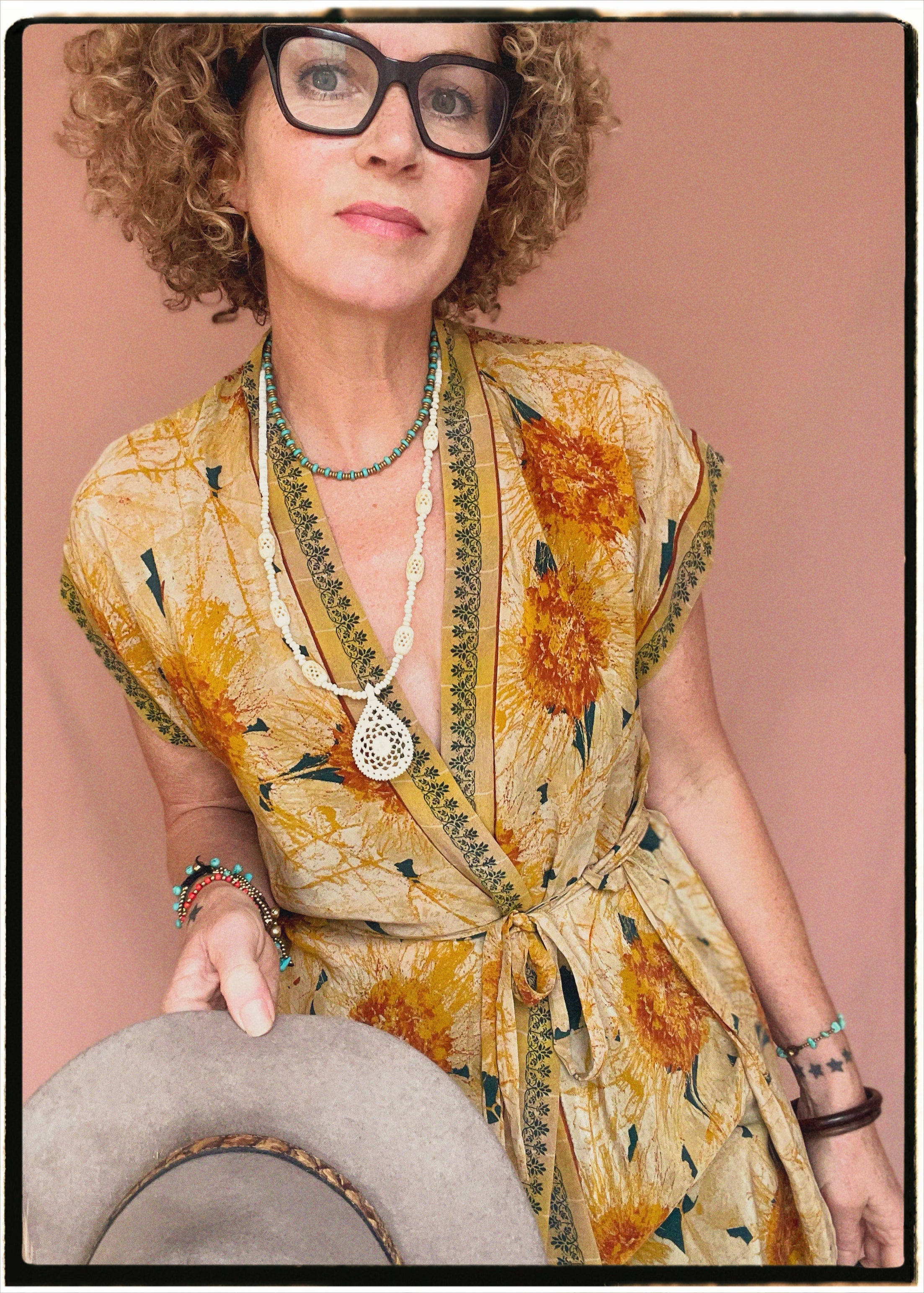Woman wearing a bohemian style balloon sleeved patterned blouse made from vintage repurposed Indian silk crepe sari in front of a plain background
