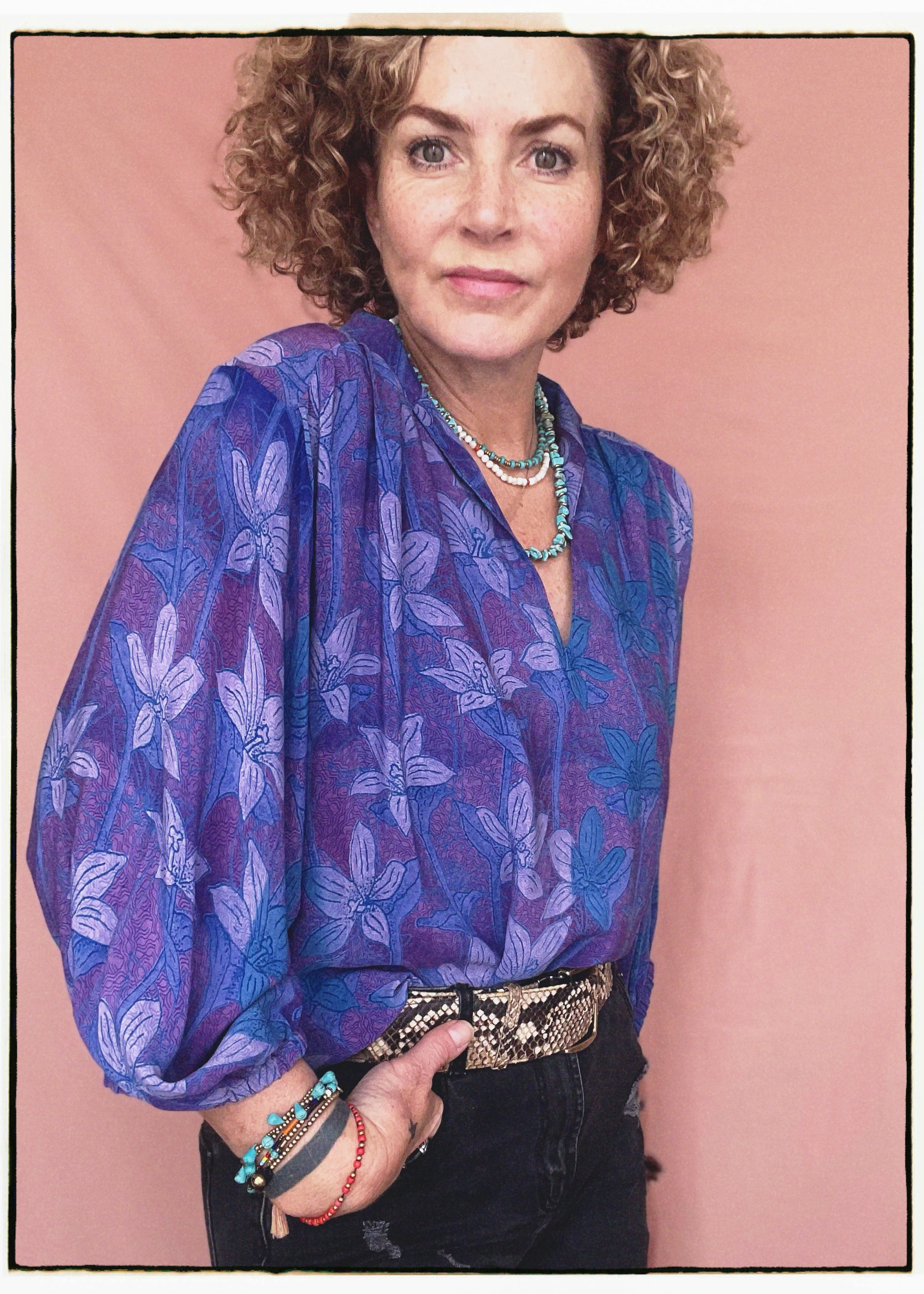 Woman wearing a bohemian style balloon sleeved patterned blouse made from vintage repurposed Indian silk crepe sari in front of a plain background