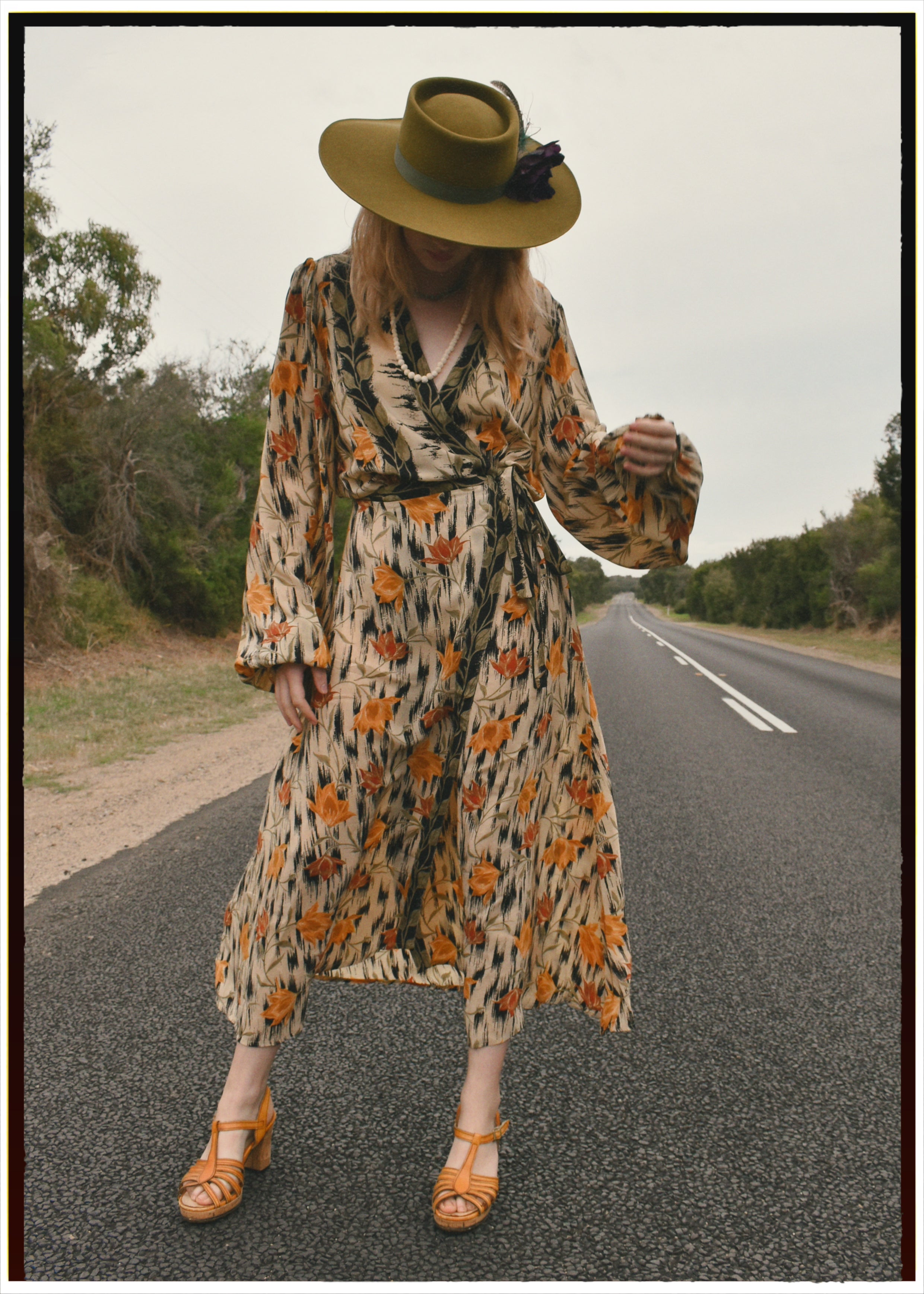 Woman wearing a bohemian style balloon sleeved wrap dress made from vintage repurposed Indian silk crepe sari in front of a plain