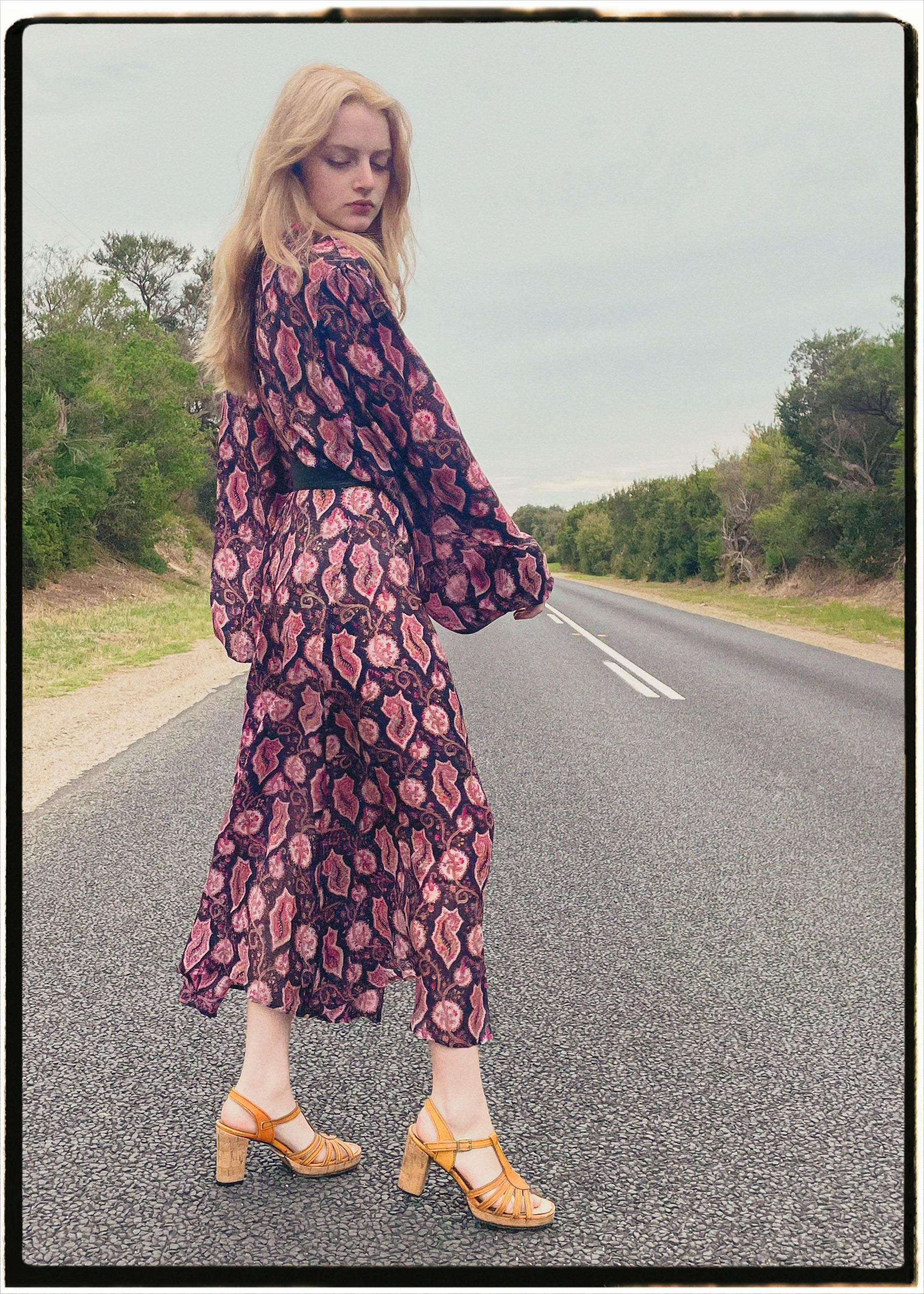 Woman wearing a bohemian style balloon sleeved wrap dress made from vintage repurposed Indian silk crepe sari in front of a plain