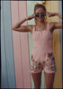 bohemian vintage retro style playsuit, beach suit bathing suit with shell buttons and pink material, hand embroidered with Hawaii tiki style hula gils and hibiscus flowers
