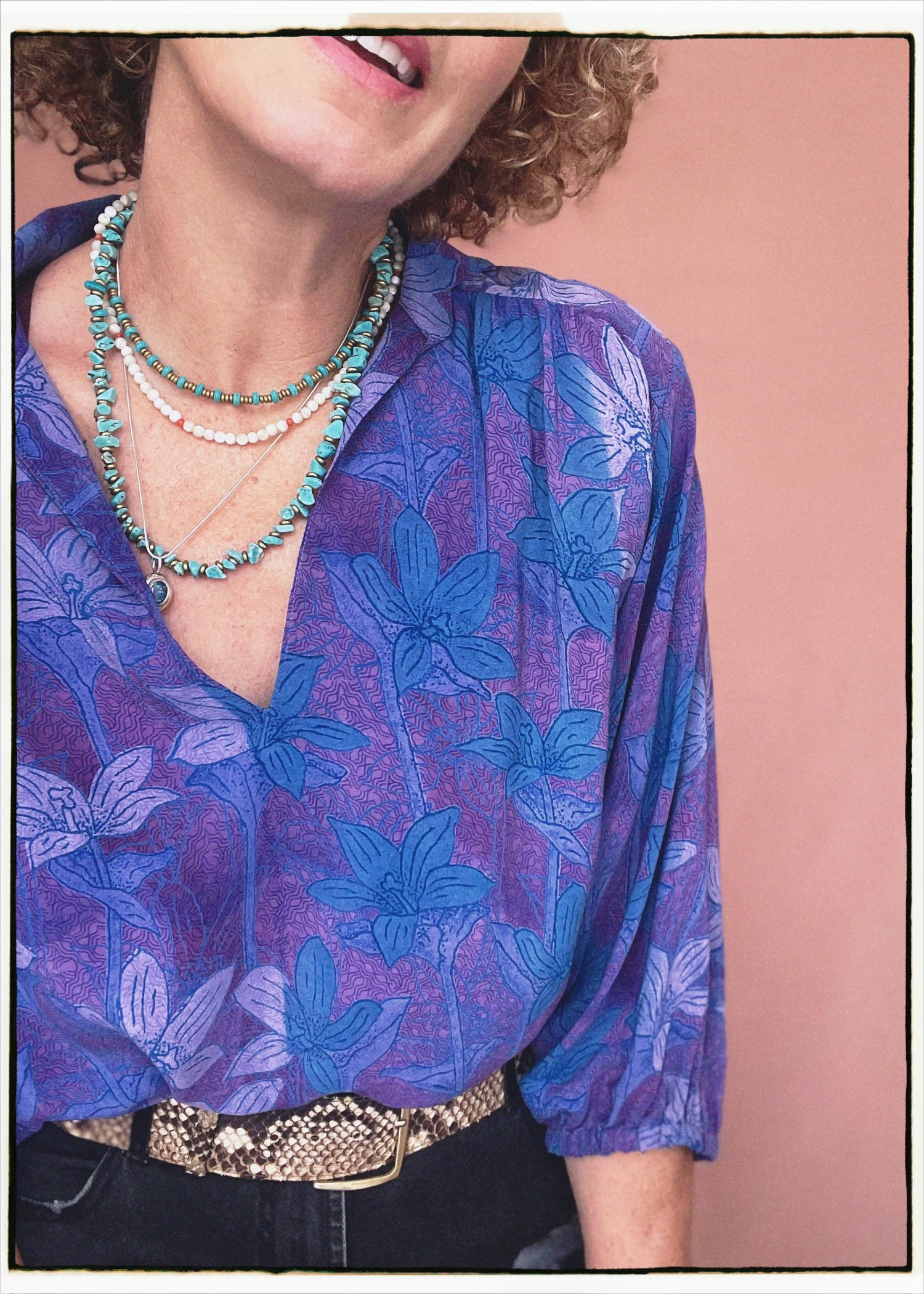 Woman wearing a bohemian style balloon sleeved patterned blouse made from vintage repurposed Indian silk crepe sari in front of a plain background