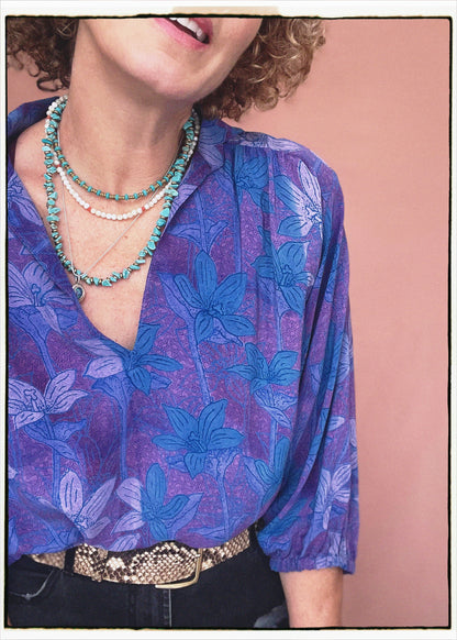Woman wearing a bohemian style balloon sleeved patterned blouse made from vintage repurposed Indian silk crepe sari in front of a plain background