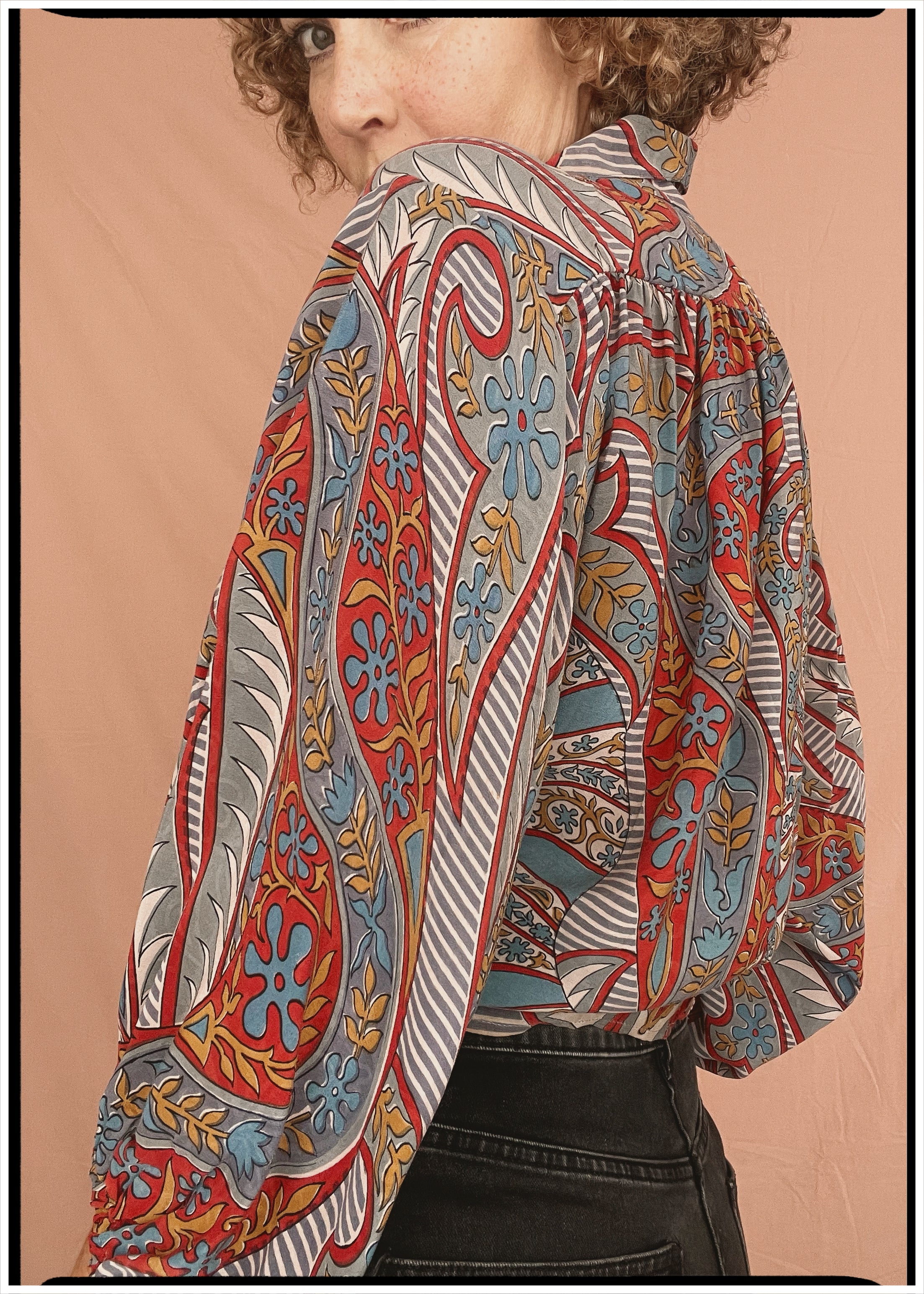 Woman wearing a bohemian style balloon sleeved patterned blouse made from vintage repurposed Indian silk crepe sari in front of a plain background