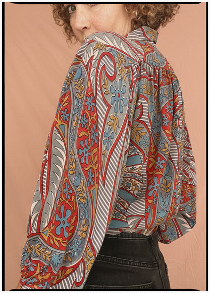 Woman wearing a bohemian style balloon sleeved patterned blouse made from vintage repurposed Indian silk crepe sari in front of a plain background