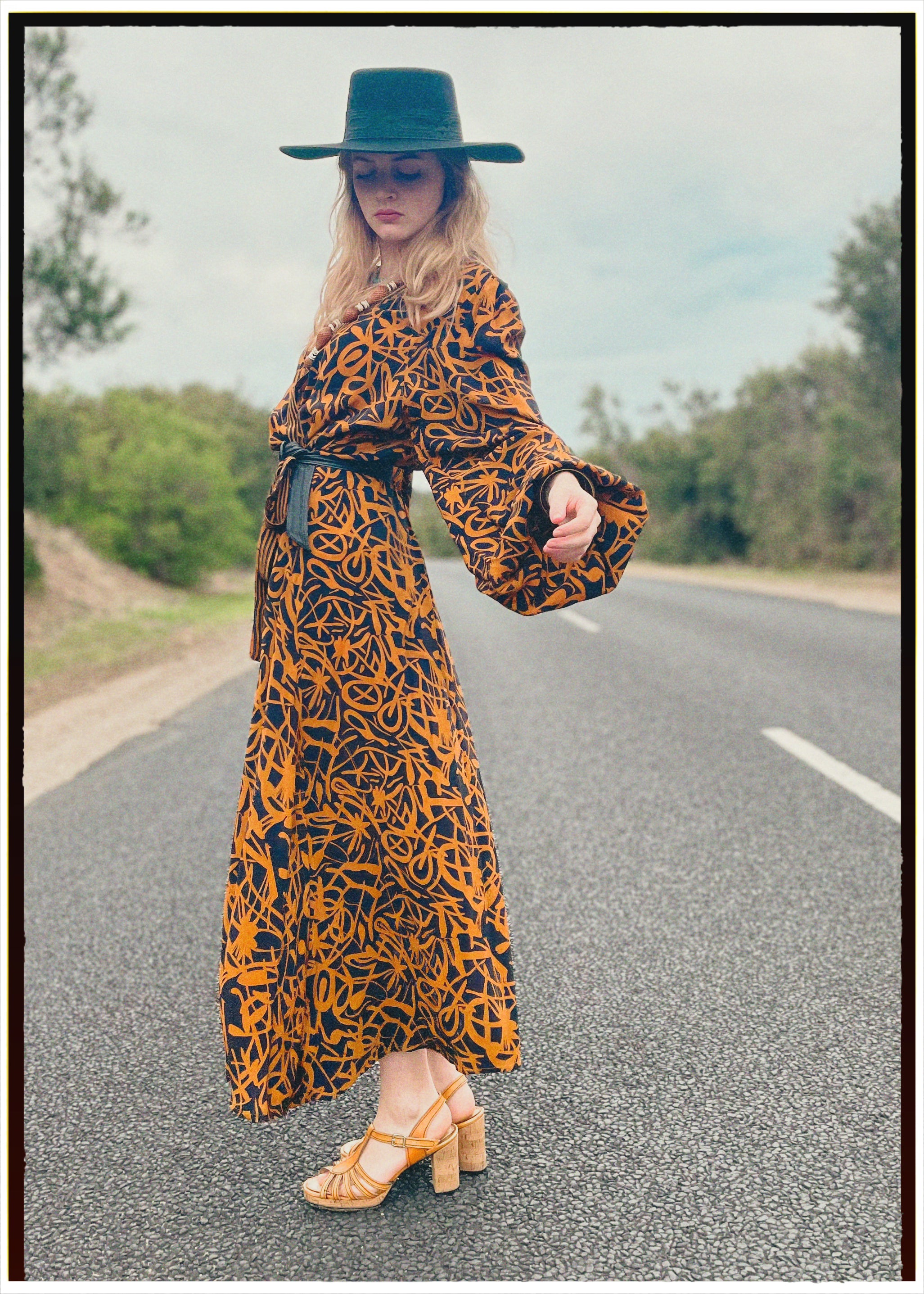 Woman wearing a bohemian style balloon sleeved wrap dress made from vintage repurposed Indian silk crepe sari in front of a plain 