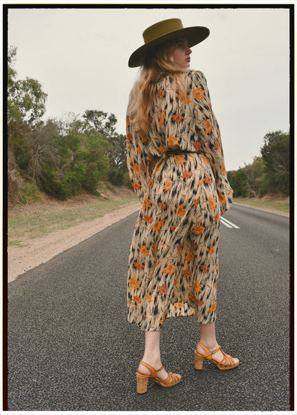 Woman wearing a bohemian style balloon sleeved wrap dress made from vintage repurposed Indian silk crepe sari in front of a plain 