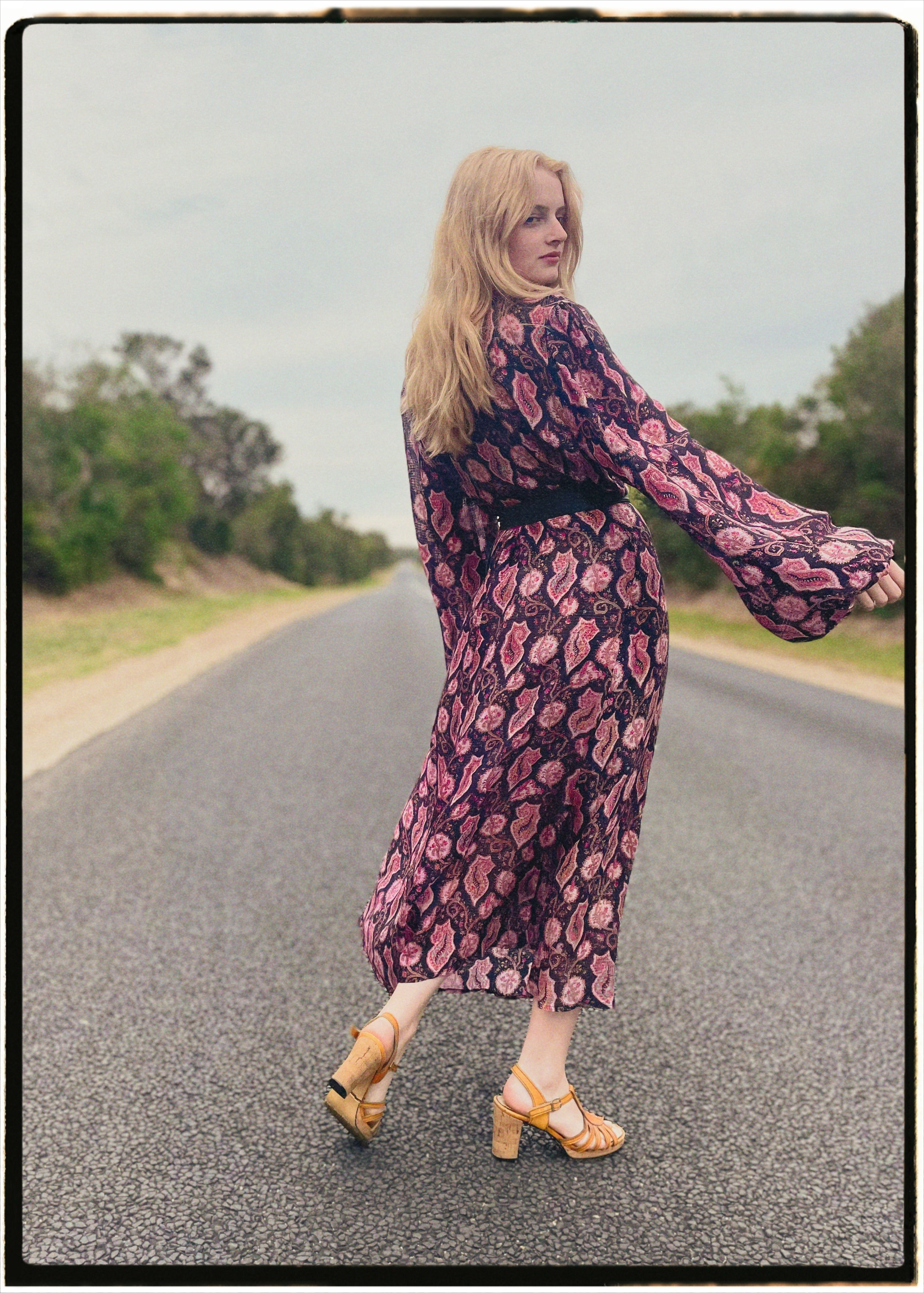 Woman wearing a bohemian style balloon sleeved wrap dress made from vintage repurposed Indian silk crepe sari in front of a plain 