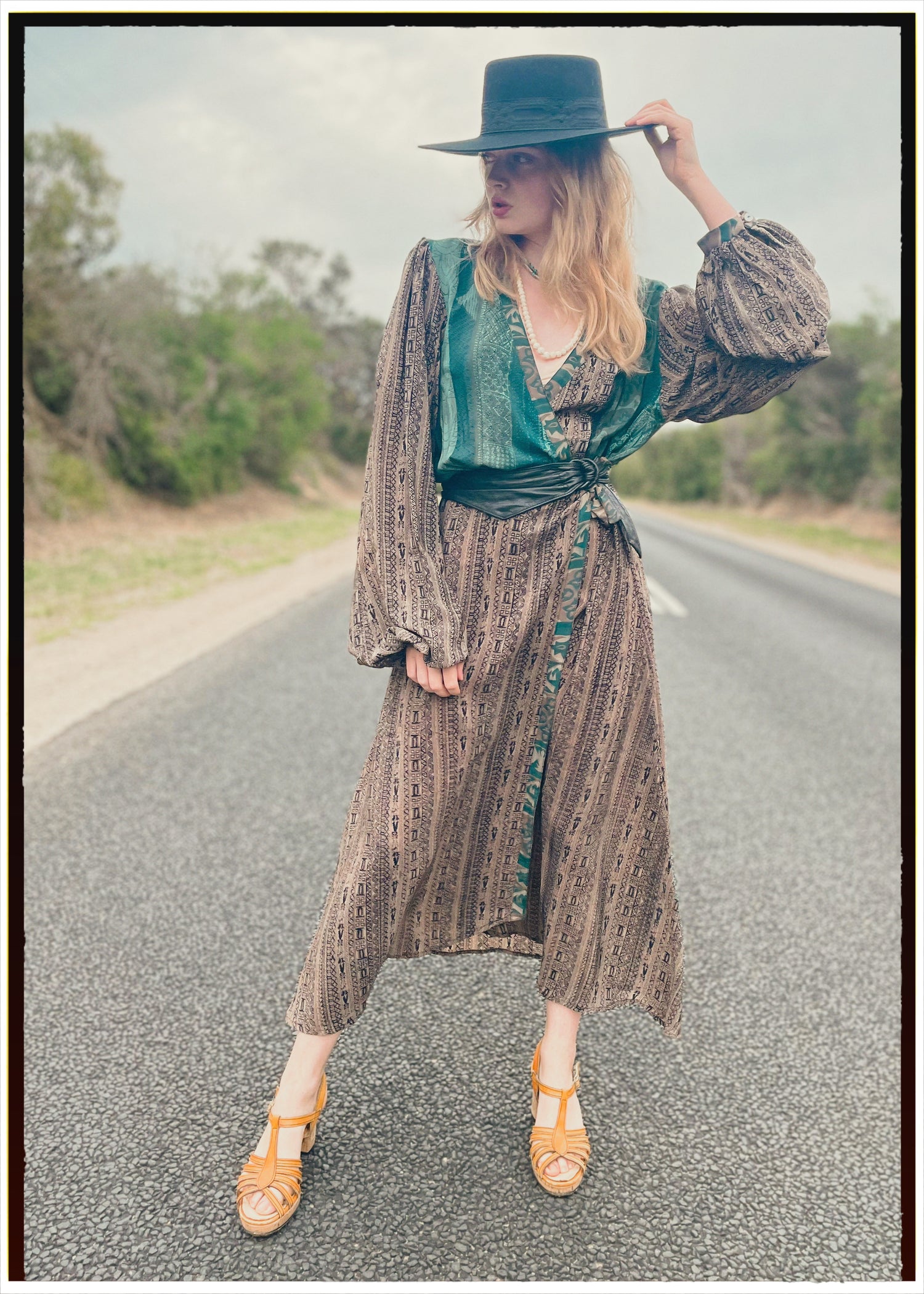 Woman wearing a bohemian style balloon sleeved wrap dress made from vintage repurposed Indian silk crepe sari in front of a plain 