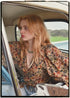Woman wearing a bohemian style balloon sleeved blouse made from vintage Indian repurposed silk crepe saree sitting in the back of a vintage car with a scenic background