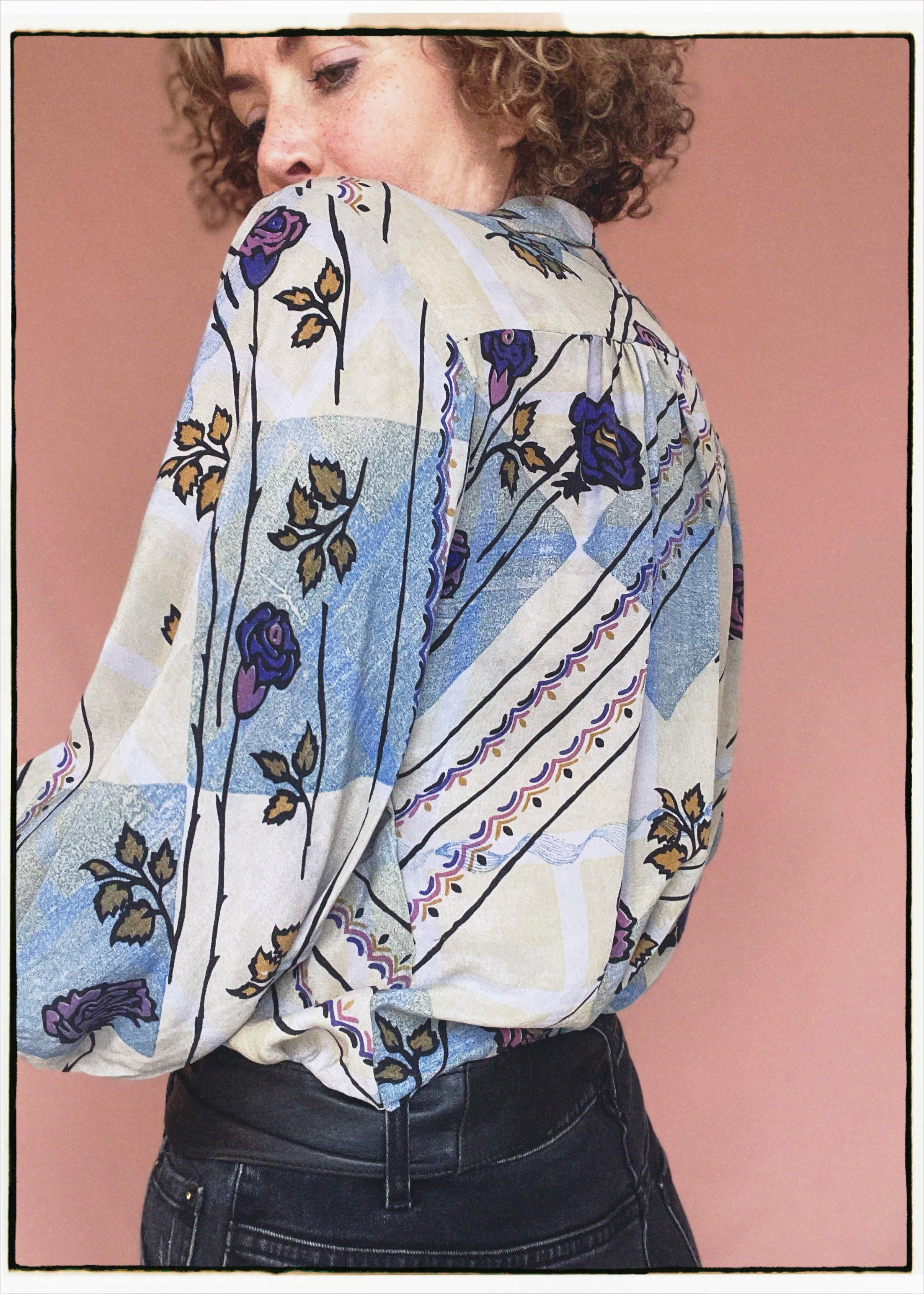 Woman wearing a bohemian style balloon sleeved patterned blouse made from vintage repurposed Indian silk crepe sari in front of a plain background