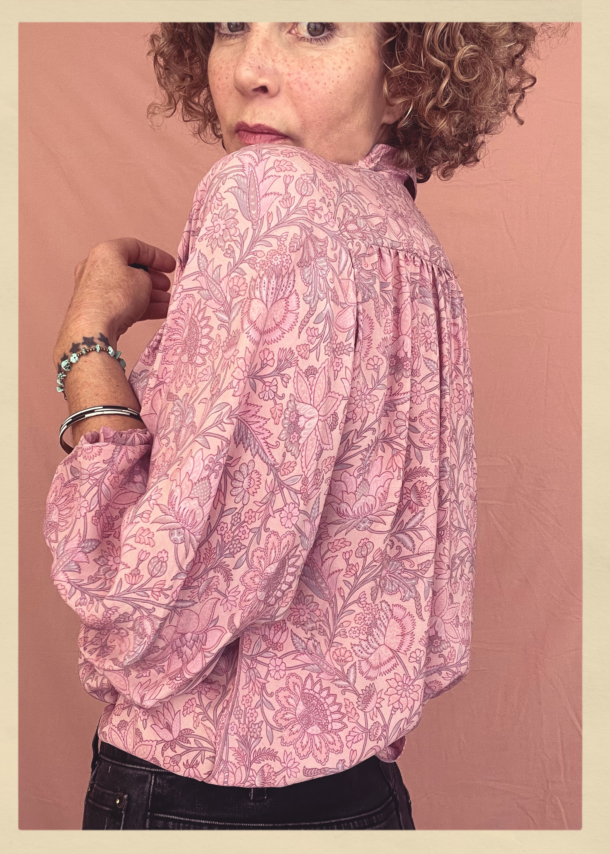 Woman wearing a bohemian style balloon sleeved patterned blouse made from vintage repurposed Indian silk crepe sari in front of a plain background