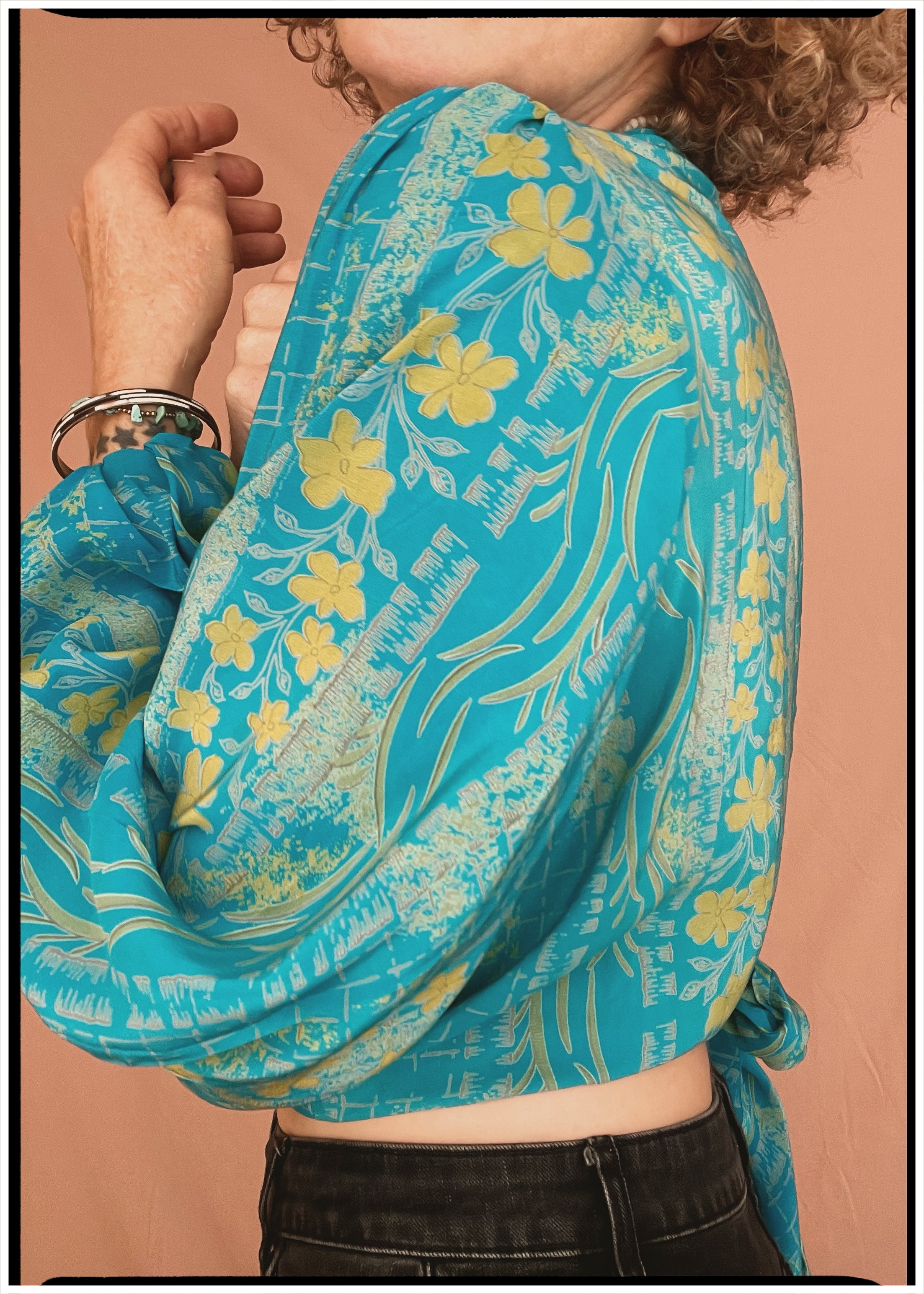 Woman wearing a bohemian style balloon sleeved patterned blouse made from vintage repurposed Indian silk crepe sari in front of a plain background