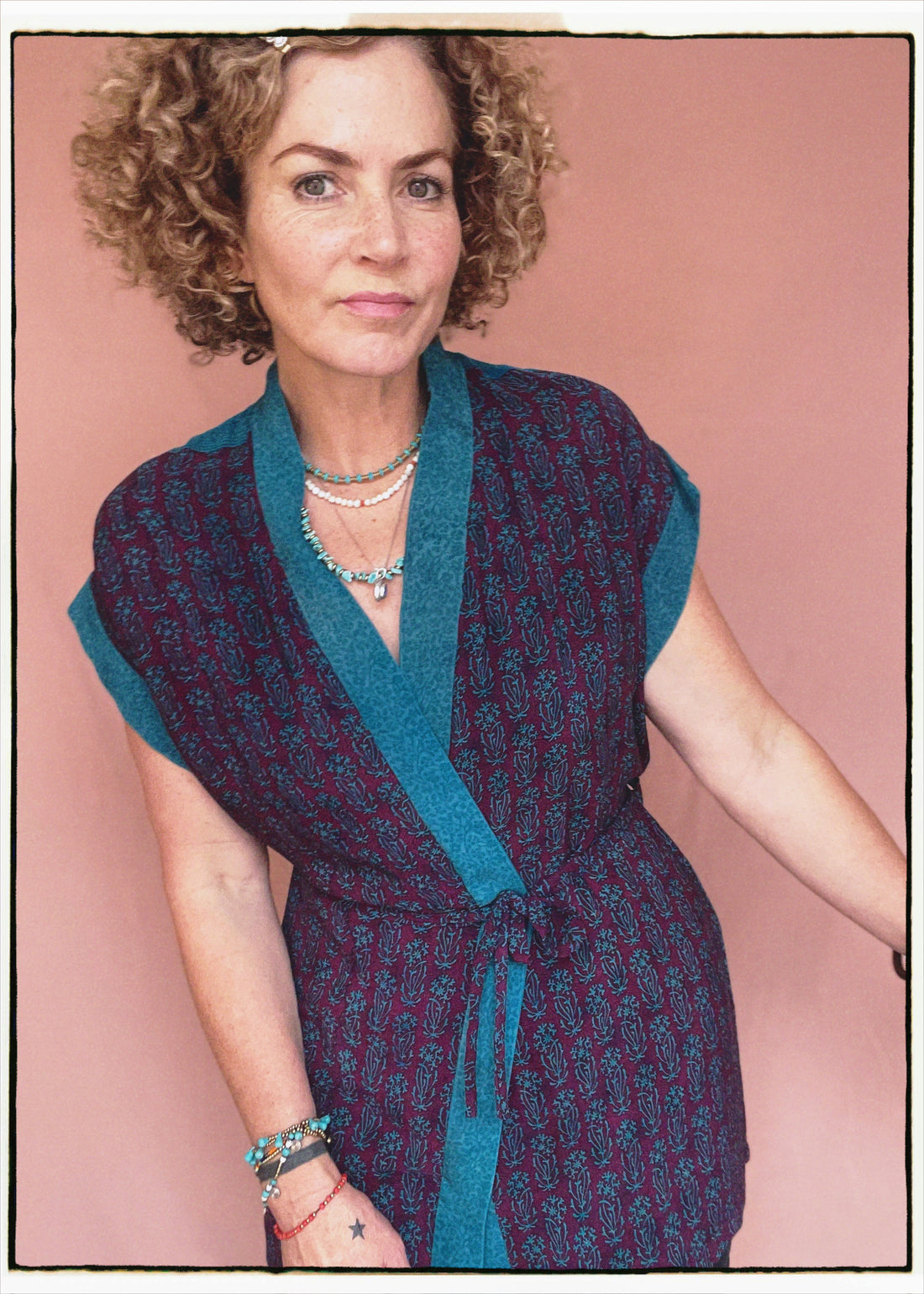 Woman wearing a bohemian style balloon sleeved patterned blouse made from vintage repurposed Indian silk crepe sari in front of a plain background