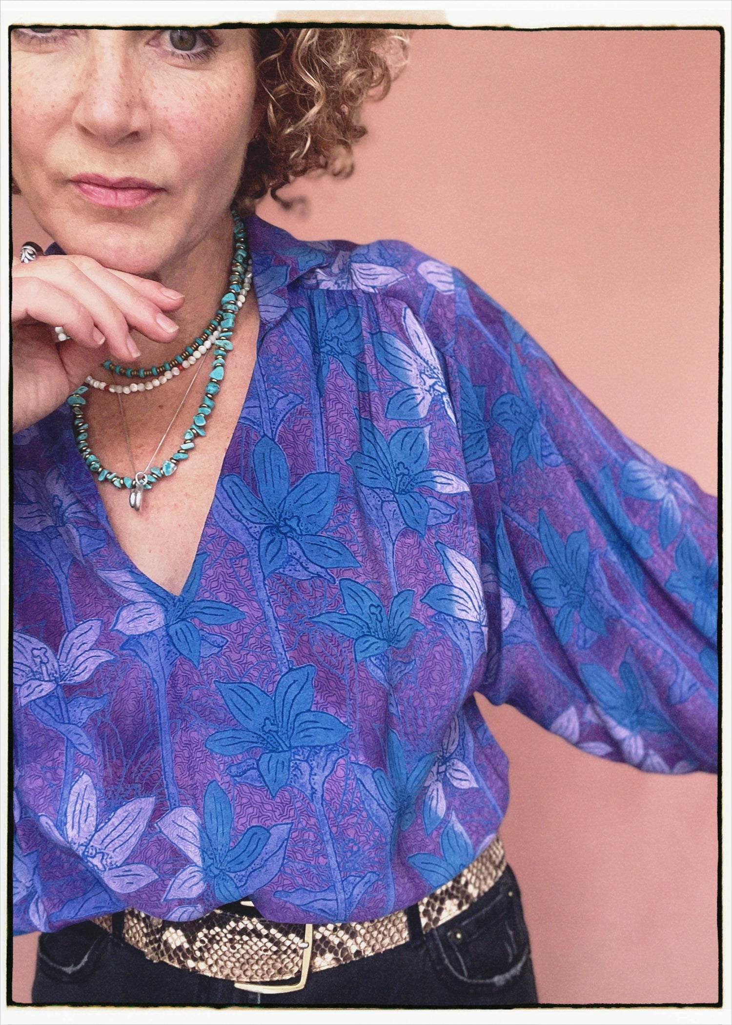 Woman wearing a bohemian style balloon sleeved patterned blouse made from vintage repurposed Indian silk crepe sari in front of a plain background