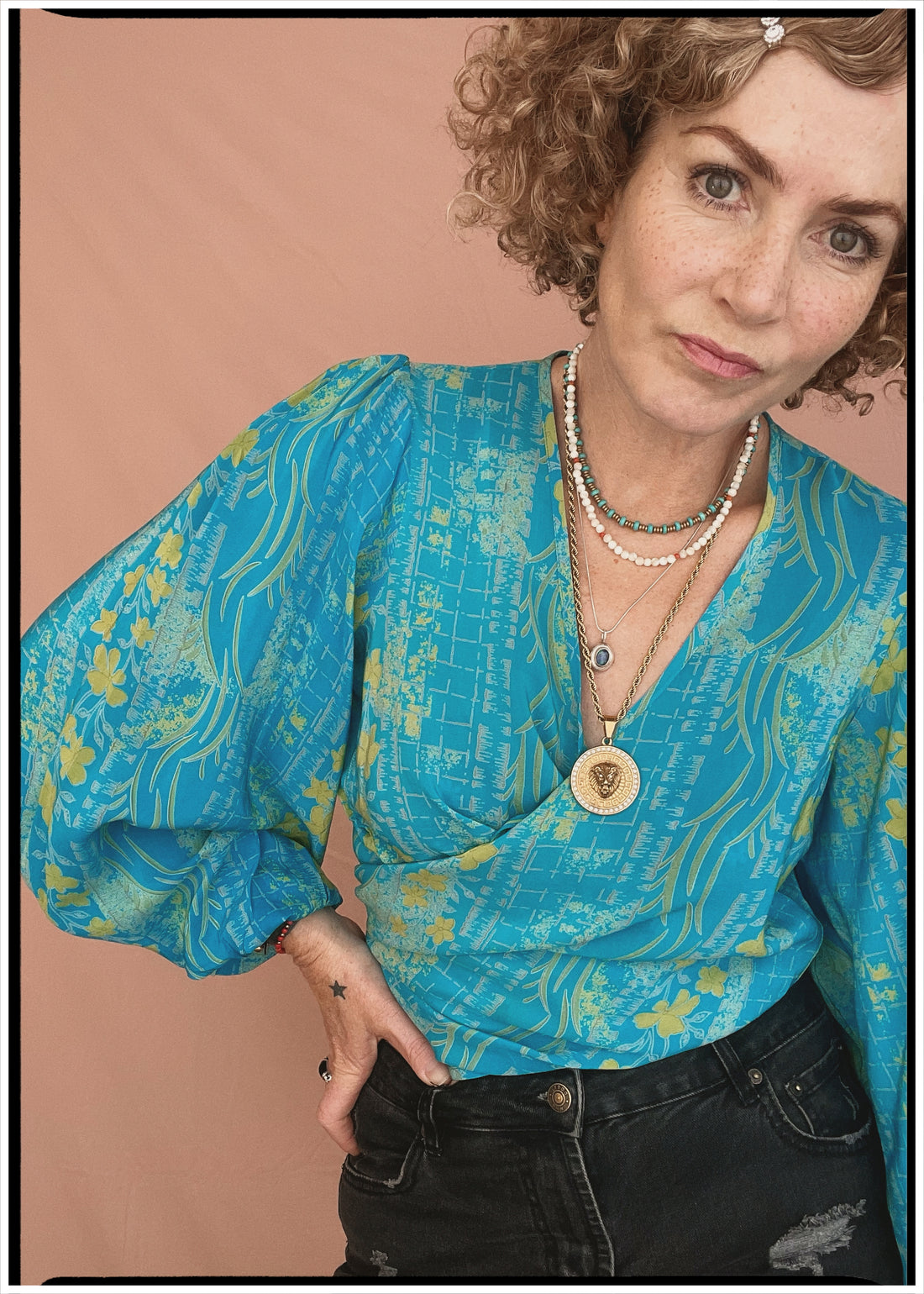 Woman wearing a bohemian style balloon sleeved patterned blouse made from vintage repurposed Indian silk crepe sari in front of a plain background