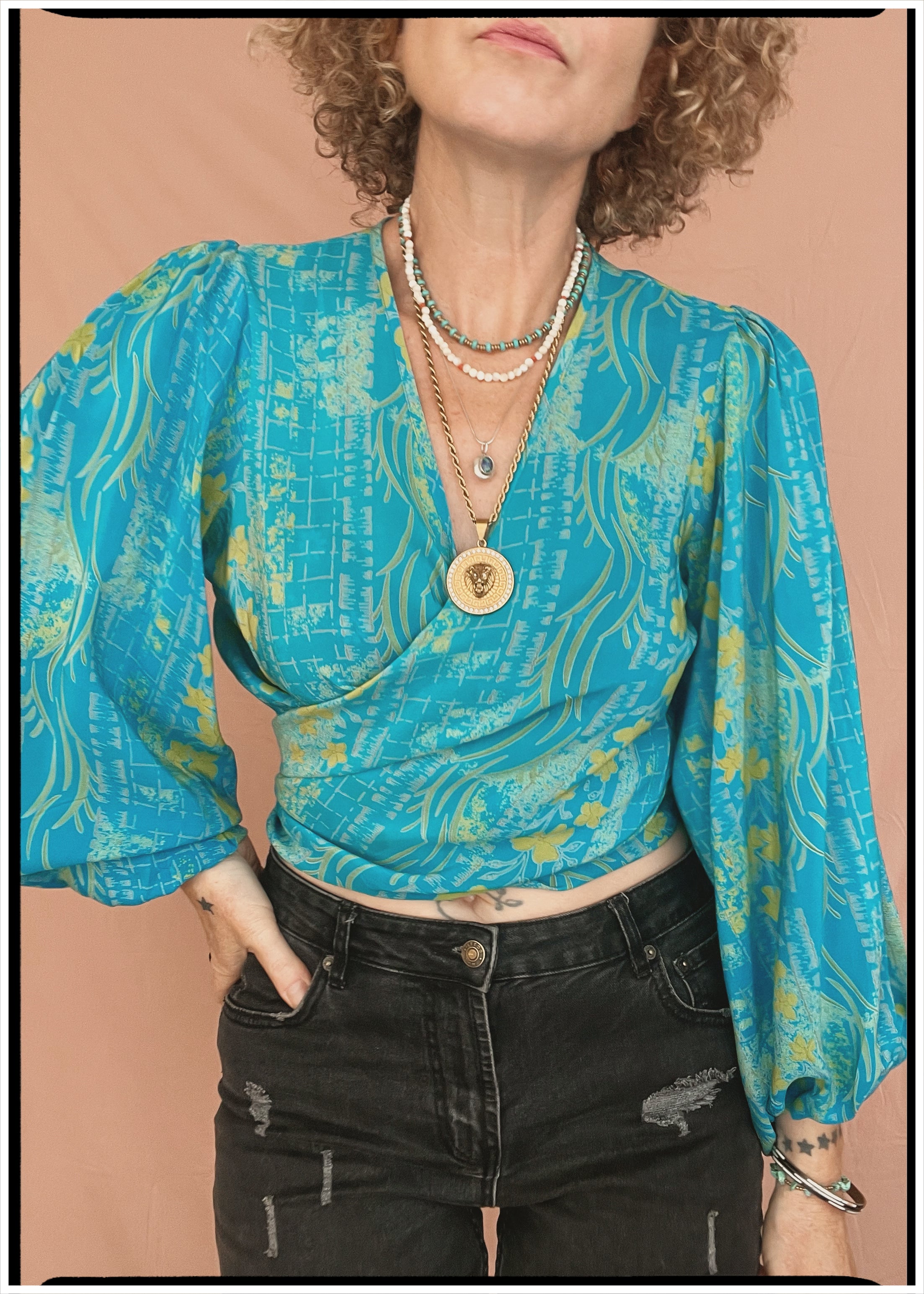 Woman wearing a bohemian style balloon sleeved patterned blouse made from vintage repurposed Indian silk crepe sari in front of a plain background