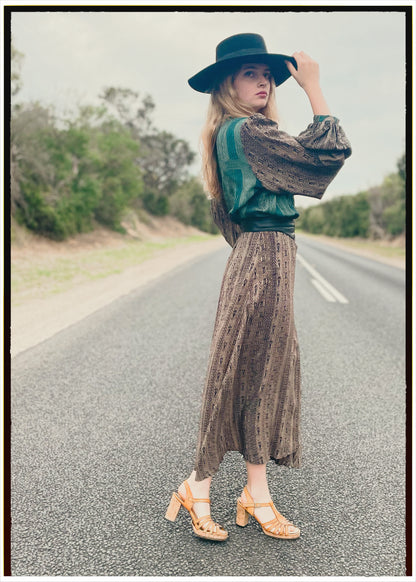 Woman wearing a bohemian style balloon sleeved wrap dress made from vintage repurposed Indian silk crepe sari in front of a plain 