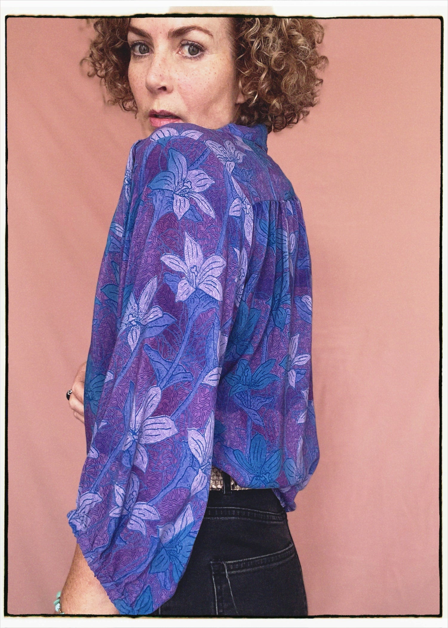 Woman wearing a bohemian style balloon sleeved patterned blouse made from vintage repurposed Indian silk crepe sari in front of a plain background