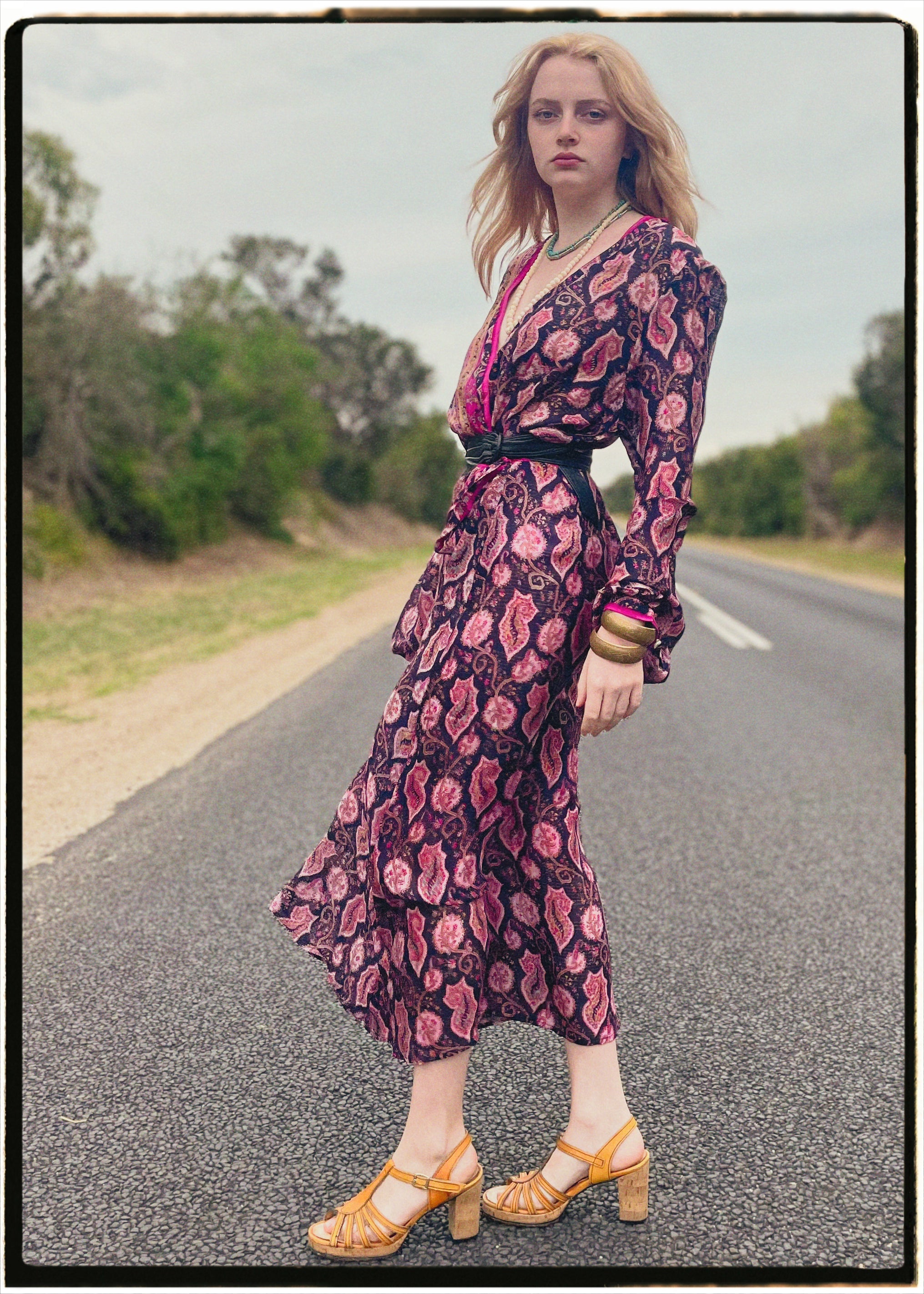 Woman wearing a bohemian style balloon sleeved wrap dress made from vintage repurposed Indian silk crepe sari in front of a plain 