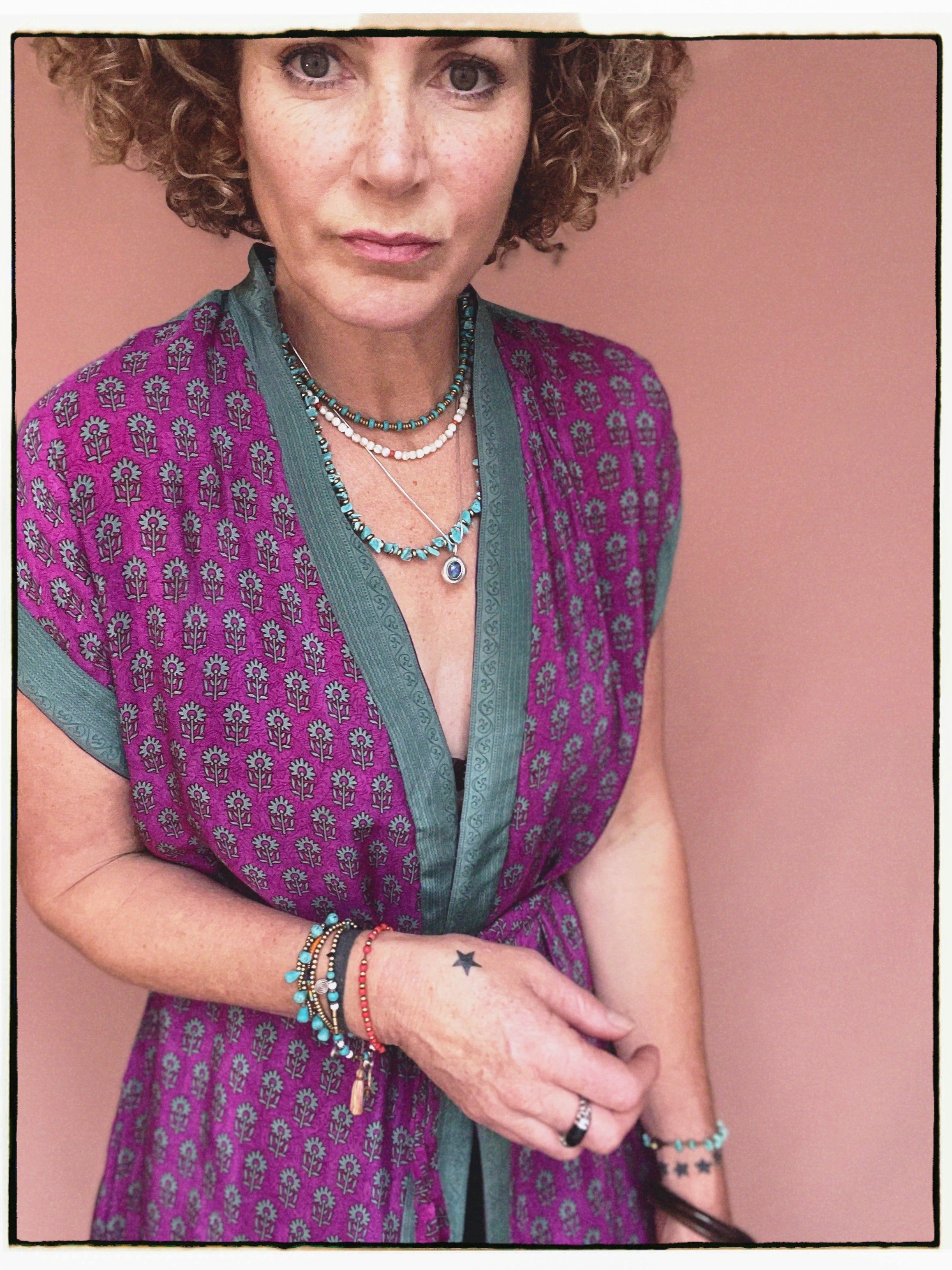 Woman wearing a bohemian style balloon sleeved patterned blouse made from vintage repurposed Indian silk crepe sari in front of a plain background
