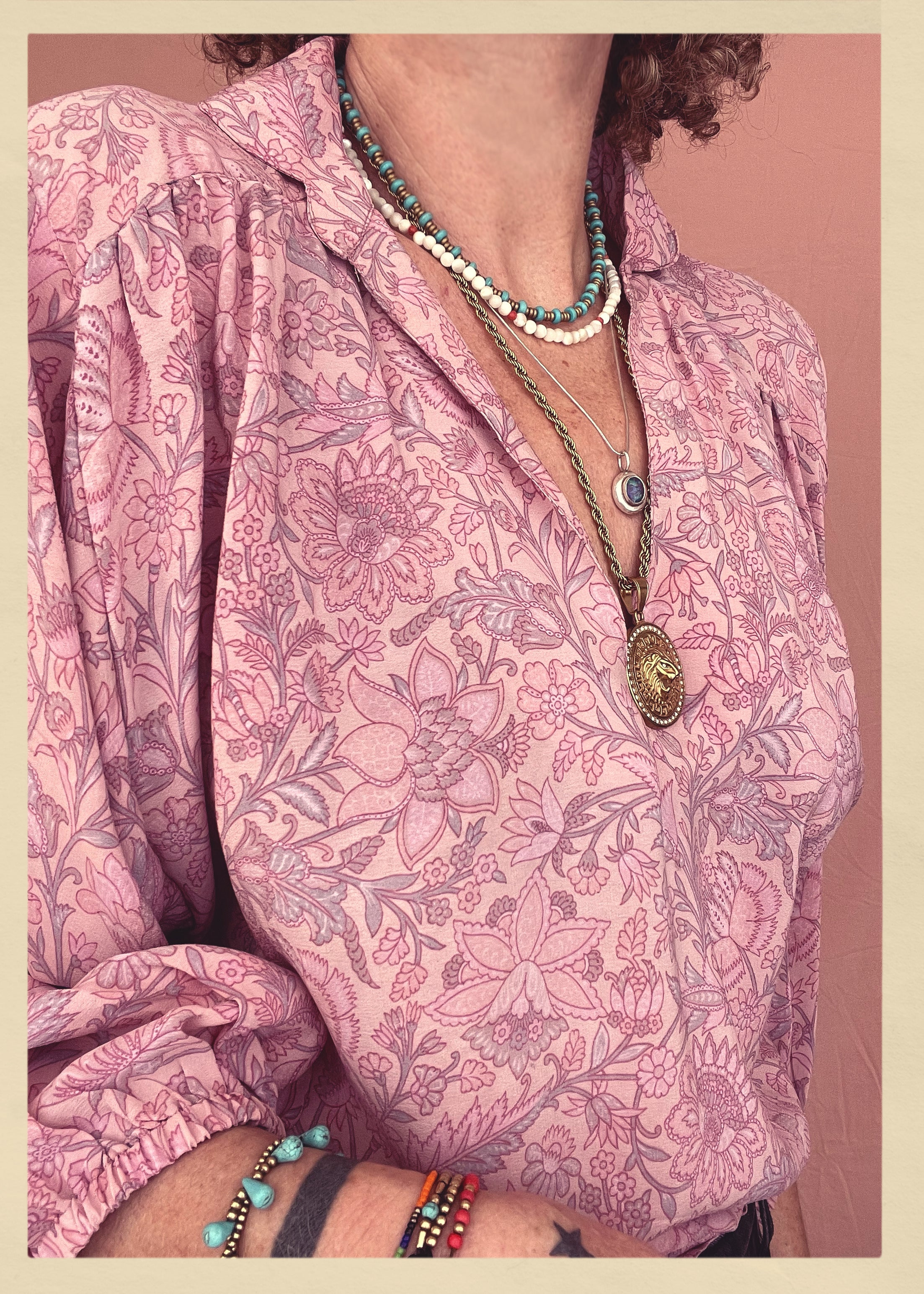 Woman wearing a bohemian style balloon sleeved patterned blouse made from vintage repurposed Indian silk crepe sari in front of a plain background