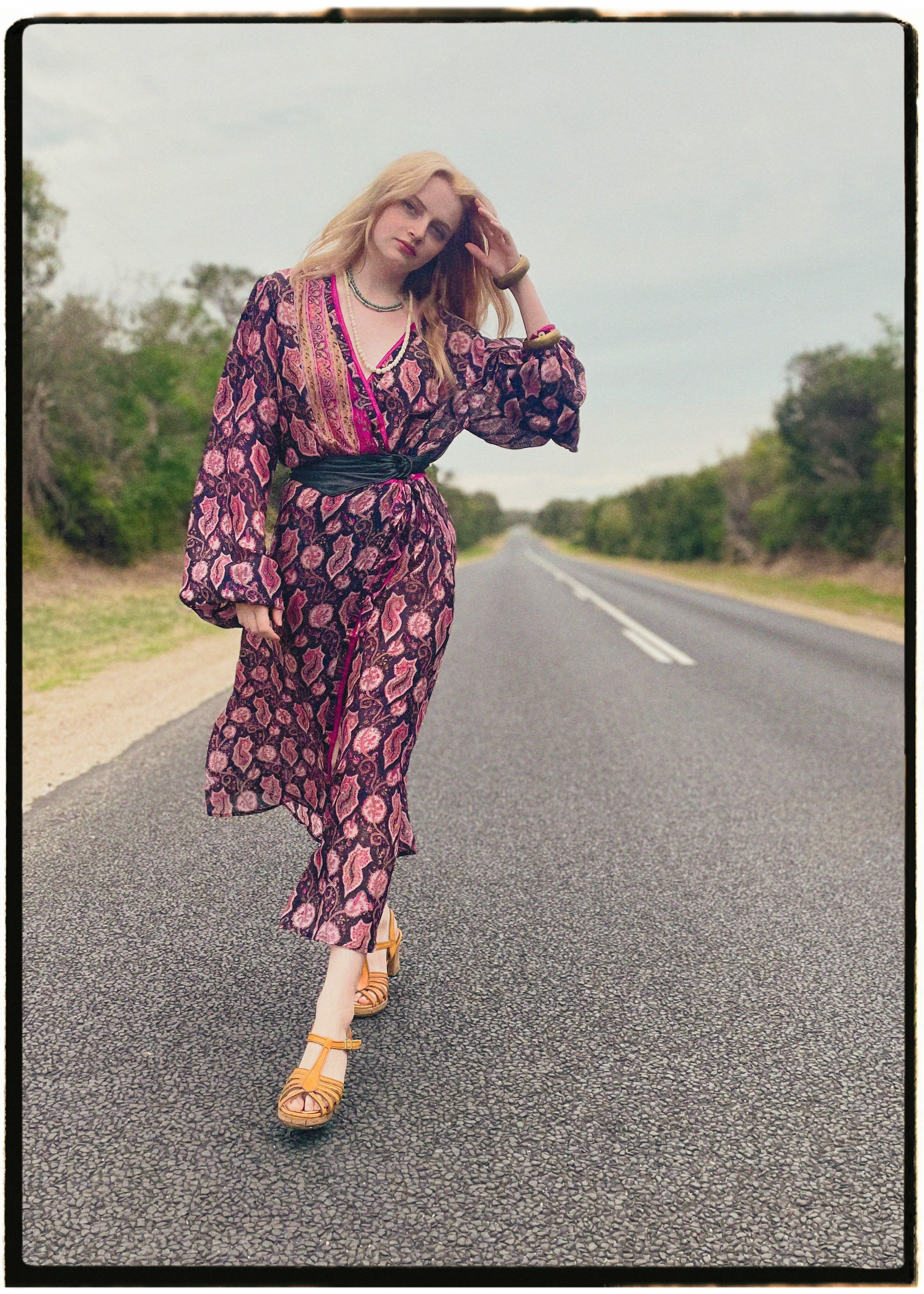 Woman wearing a bohemian style balloon sleeved wrap dress made from vintage repurposed Indian silk crepe sari in front of a plain 