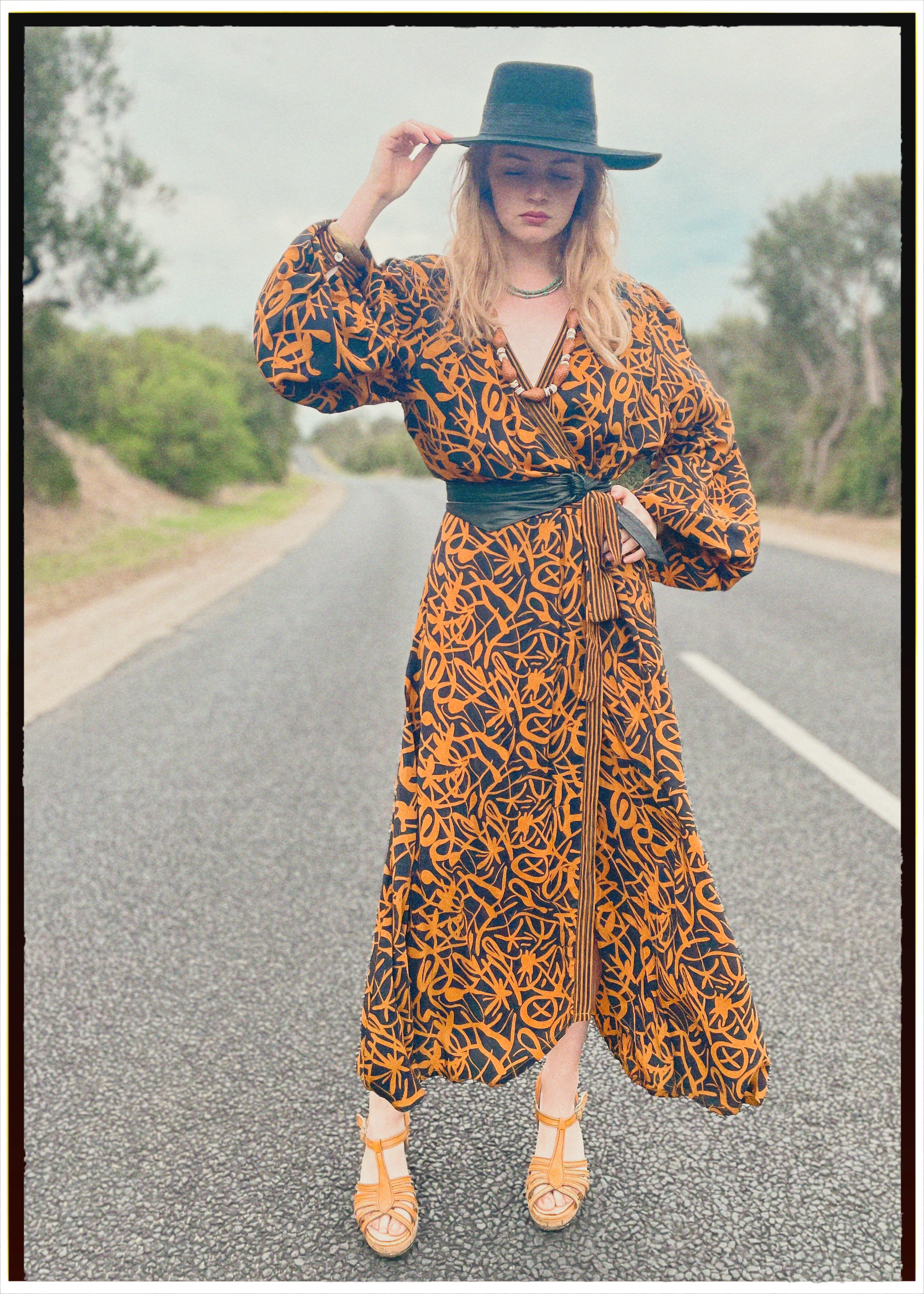 Woman wearing a bohemian style balloon sleeved wrap dress made from vintage repurposed Indian silk crepe sari in front of a plain 