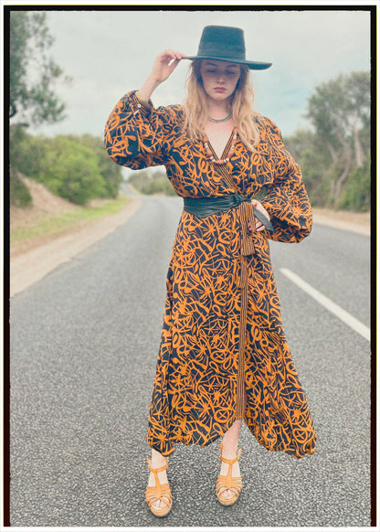 Woman wearing a bohemian style balloon sleeved wrap dress made from vintage repurposed Indian silk crepe sari in front of a plain 
