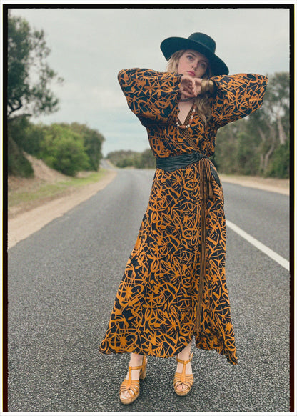 Woman wearing a bohemian style balloon sleeved wrap dress made from vintage repurposed Indian silk crepe sari in front of a plain 