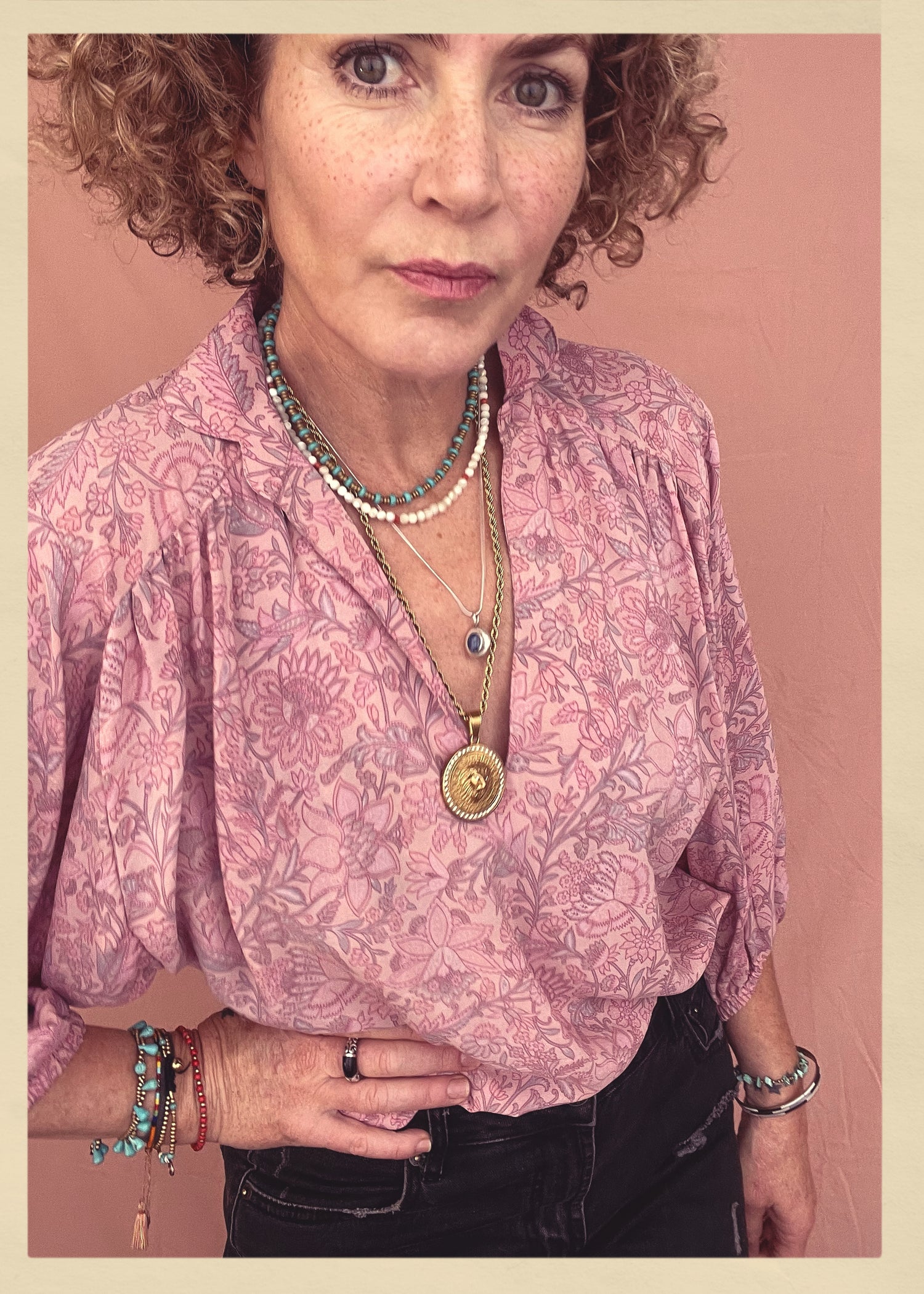 Woman wearing a bohemian style balloon sleeved patterned blouse made from vintage repurposed Indian silk crepe sari in front of a plain background