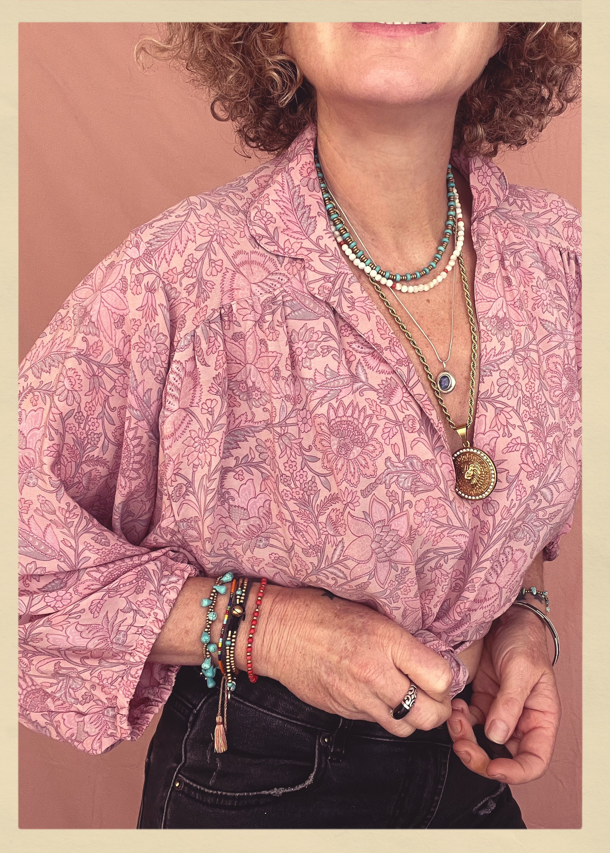 Woman wearing a bohemian style balloon sleeved patterned blouse made from vintage repurposed Indian silk crepe sari in front of a plain background