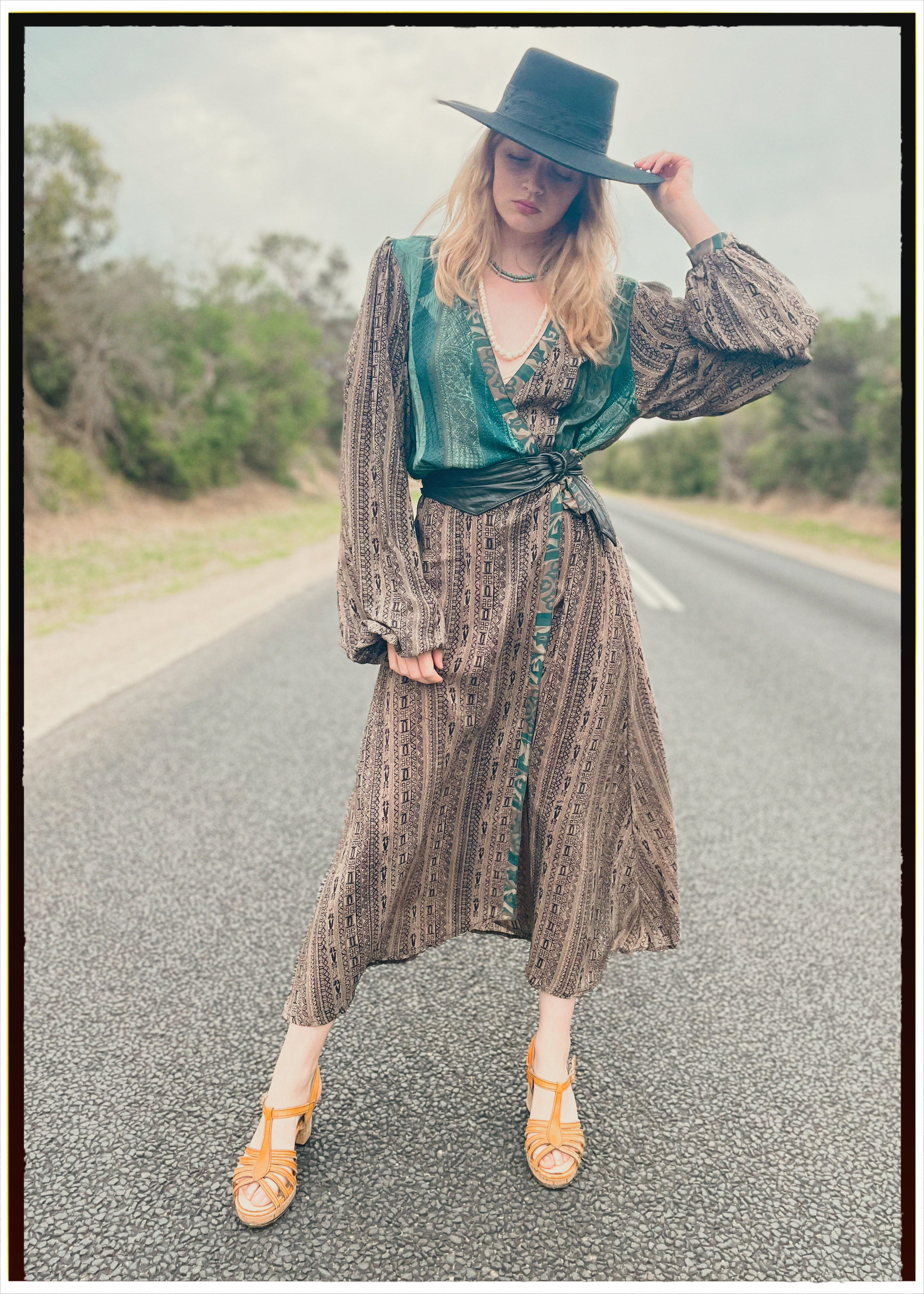 Woman wearing a bohemian style balloon sleeved wrap dress made from vintage repurposed Indian silk crepe sari in front of a plain 