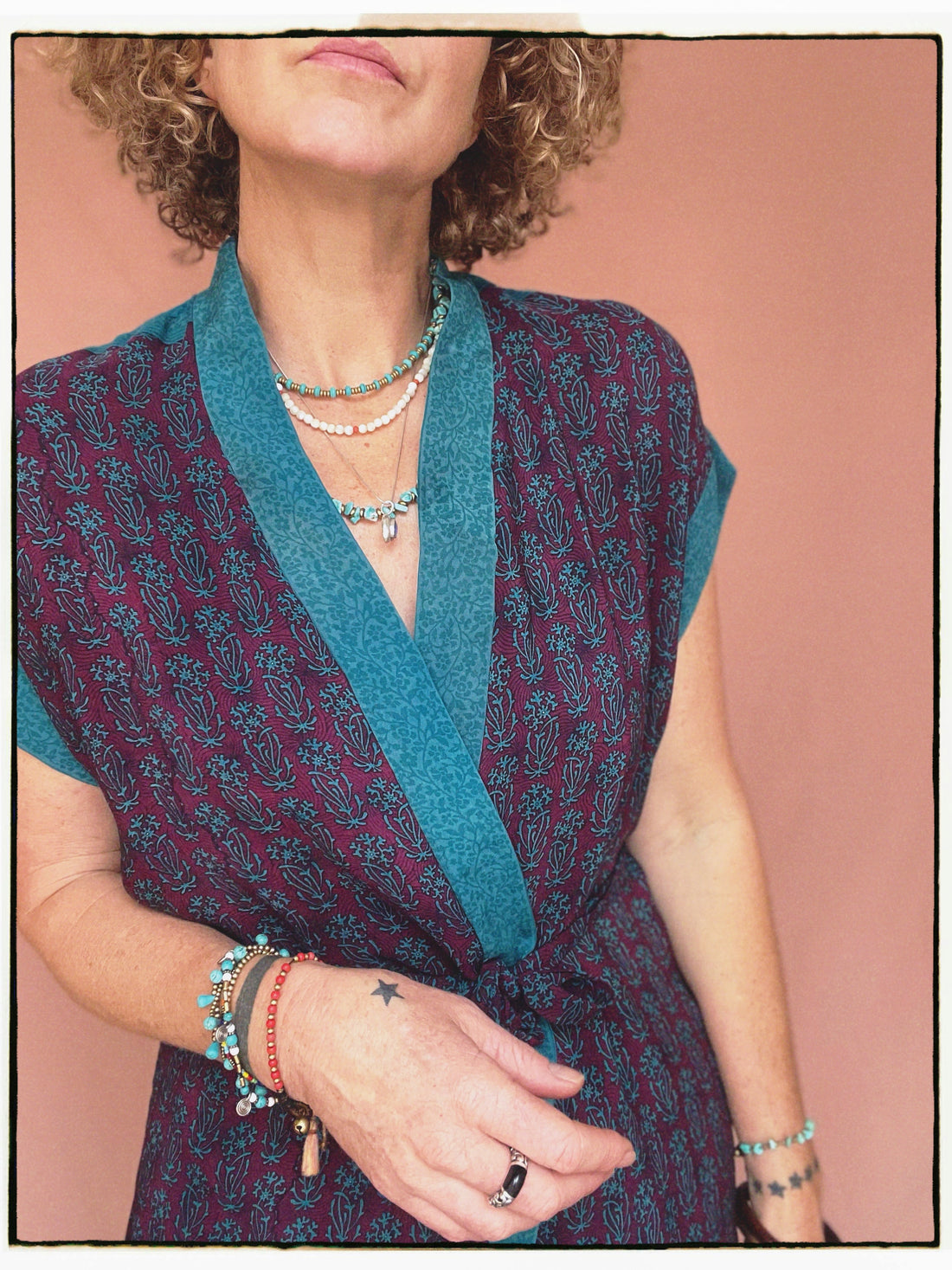 Woman wearing a bohemian style balloon sleeved patterned blouse made from vintage repurposed Indian silk crepe sari in front of a plain background