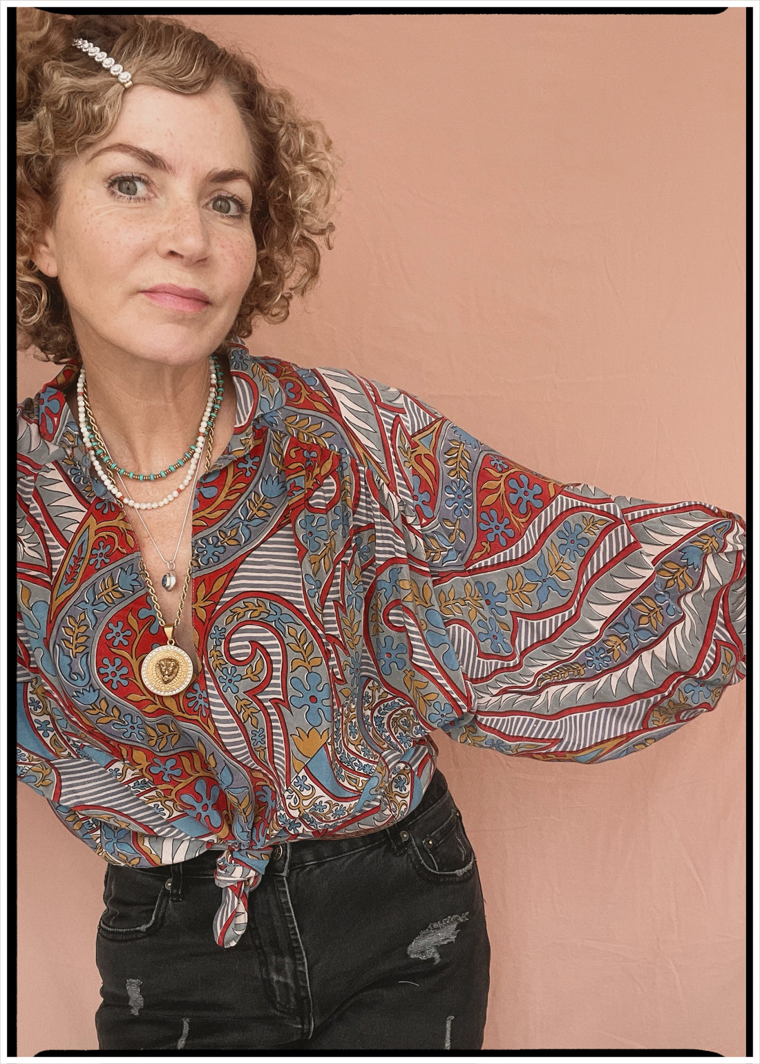 Woman wearing a bohemian style balloon sleeved patterned blouse made from vintage repurposed Indian silk crepe sari in front of a plain background