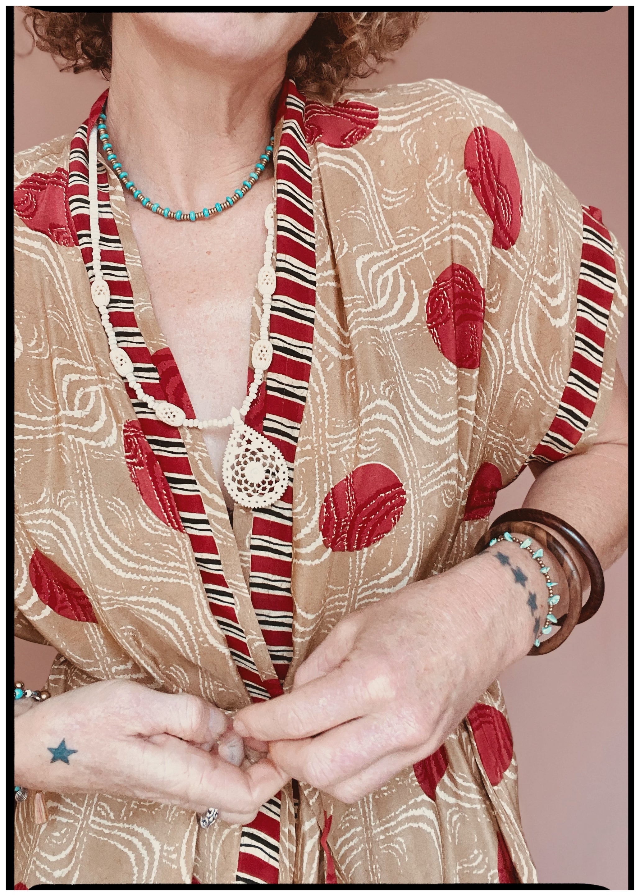 Woman wearing a bohemian style balloon sleeved patterned blouse made from vintage repurposed Indian silk crepe sari in front of a plain background