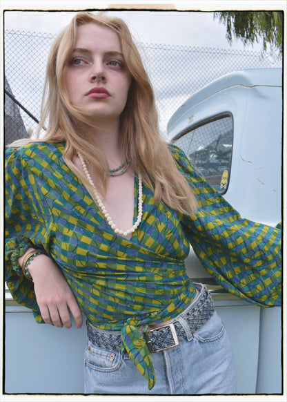 Woman wearing a bohemian style balloon sleeved blouse made from vintage Indian repurposed silk crepe saree sitting in the back of a vintage car with a scenic background