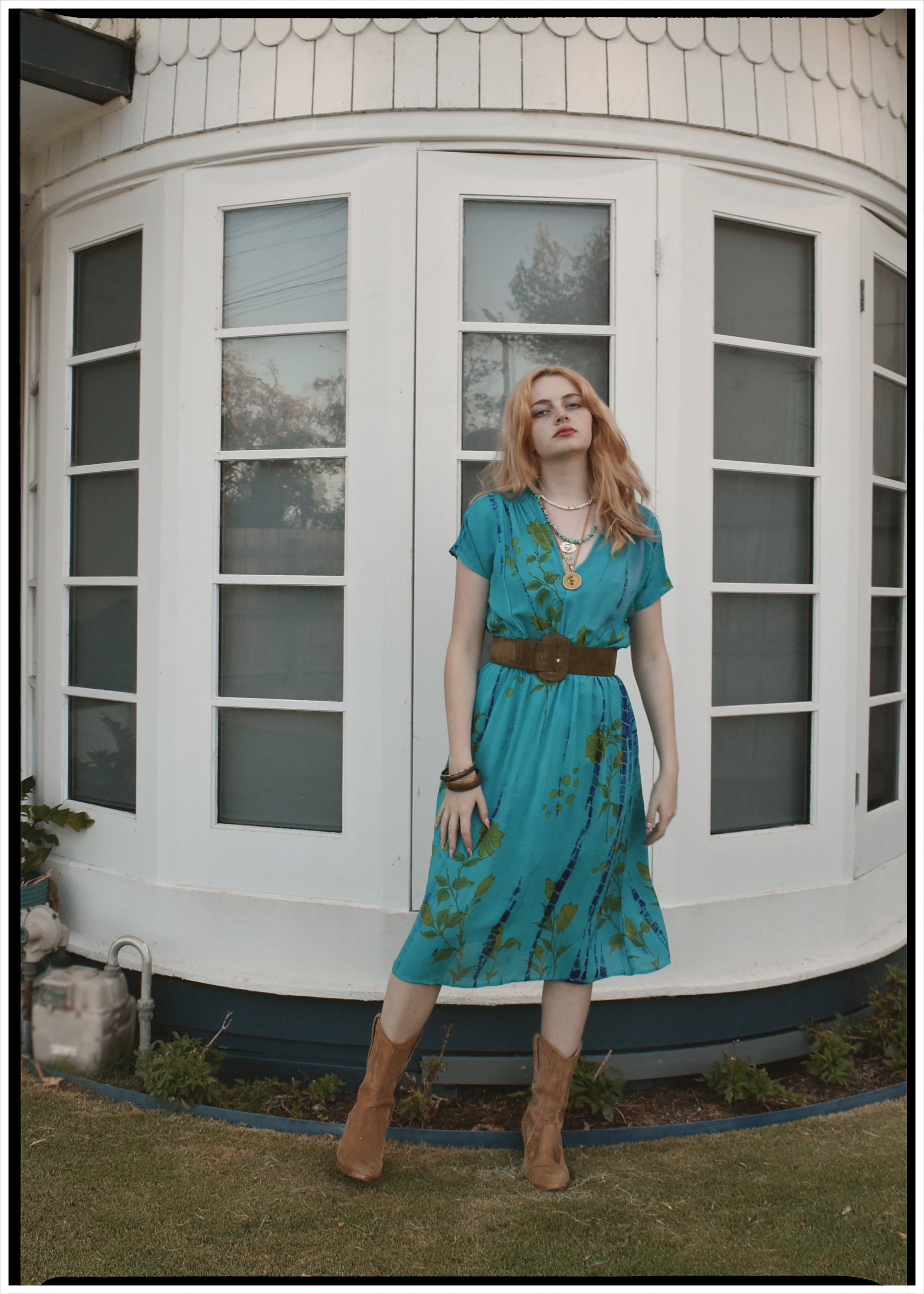 Woman in a blue dress standing in front of a white building with large windows.