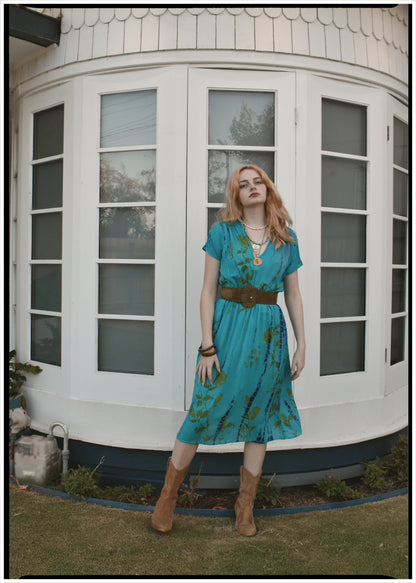 Woman in a blue dress standing in front of a white building with large windows.