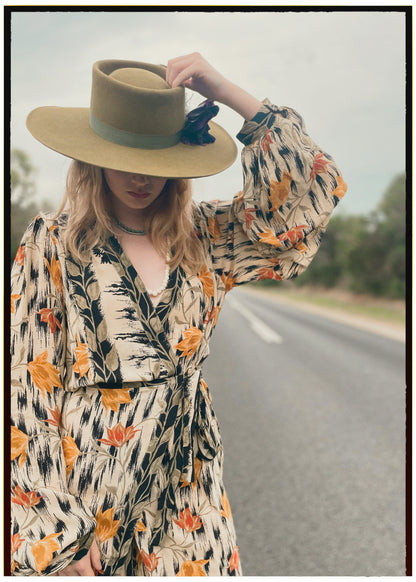 Woman wearing a bohemian style balloon sleeved wrap dress made from vintage repurposed Indian silk crepe sari in front of a plain 